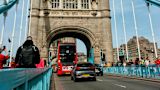 Decorative image of London bridge with pedestrians and traffic crossing on a bright day