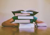 Decorative image of person behind stack of books for article