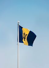 A Barbados flag against a blue sky
