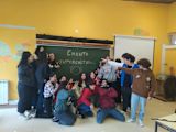 Children in a classroom point at a blackboard