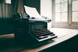 Picture of an manual vintage typewriter with a blank page on a table for article.