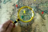 Decorative image of a magnifying glass against a world map for Using SDGs for Government Action lesson 4.3