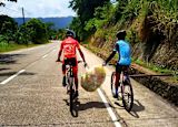 Two individuals carrying rubbish together whilst riding bikes