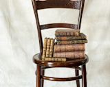 Decorative image of old books on a wooden chair for article