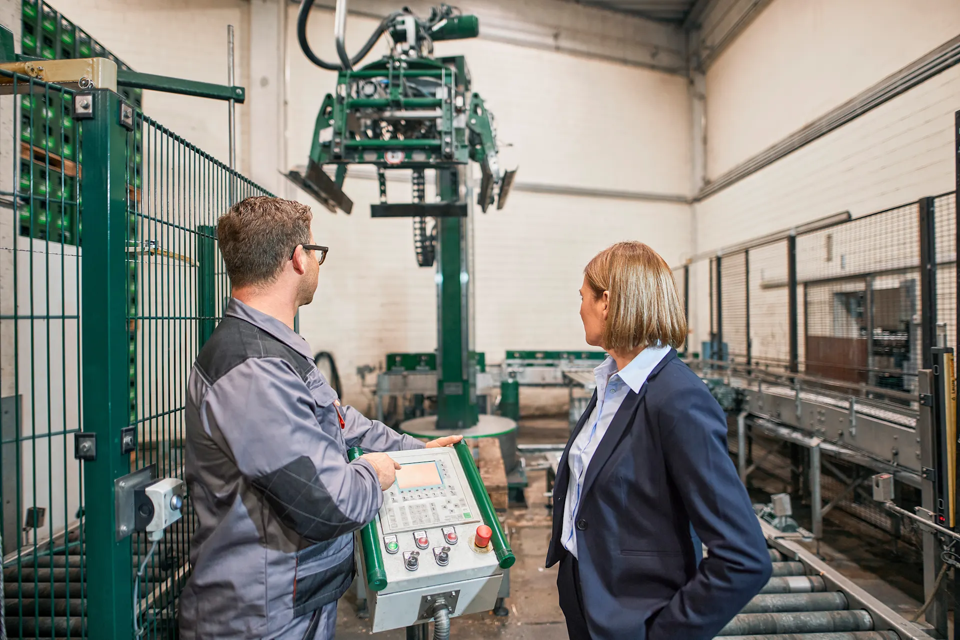 Funktion eines Palettieres mit Industriestrom Ein Mitarbeiter in einem Brauhaus zeigt die Funktion eines Palettieres mit Industriestrom seiner Geschäftsführerin.