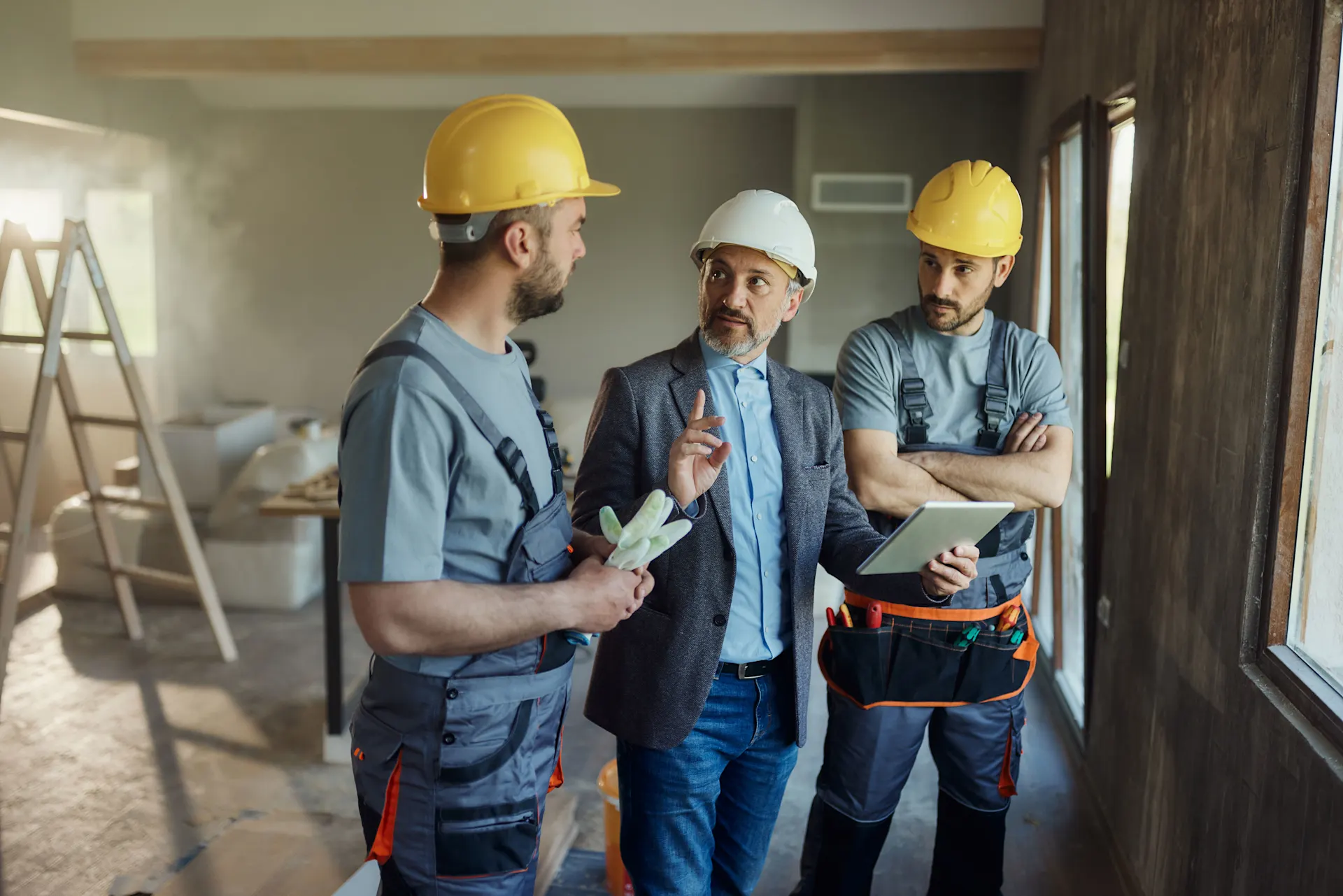 Sanierungsmaßnahmen im Haus Bauarbeiter unterhalten sich mit ihrem Auftraggeber, welche Sanierungsmaßnahmen durchgeführt werden sollen. Sanierungsfahrplan wurde mit der NEW Energie erstellt.