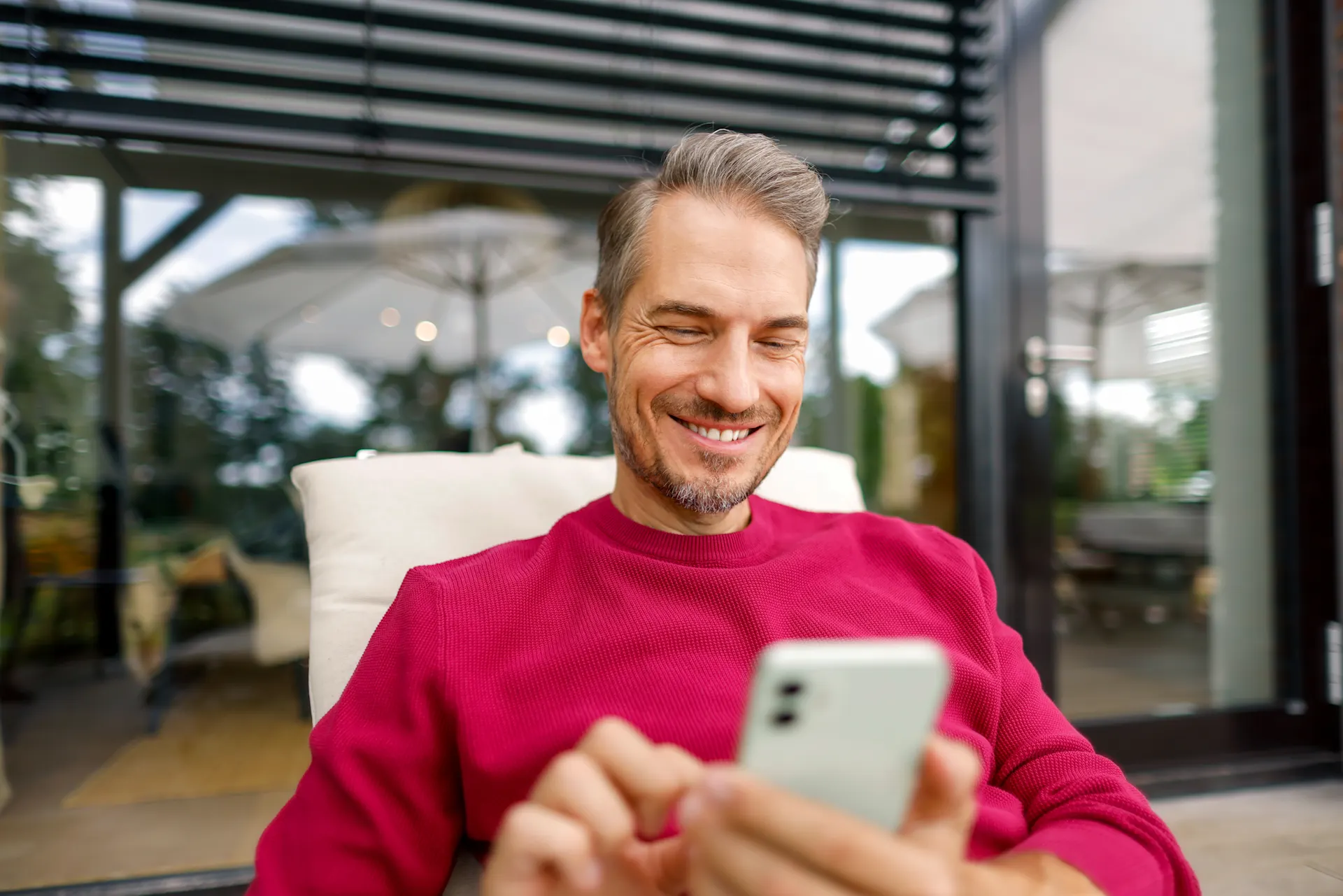 Mann mit Smartphone vergleicht Preise Ein Mann liegt mit seinem Smartphone im Liegestuhl im Garten und vergleicht die Preise der NEW Energie.