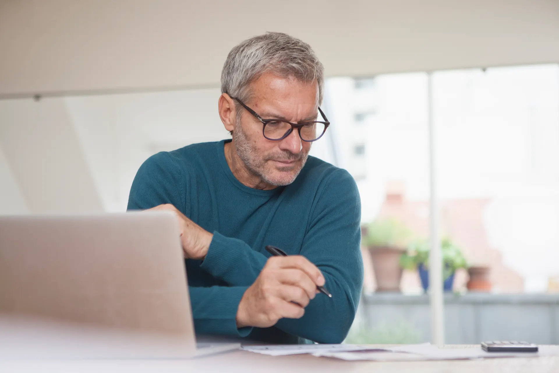 Mann an Laptop Ein Mann sitzt an einem Tisch und vergleicht am Laptop Tarife der NEW Energie.