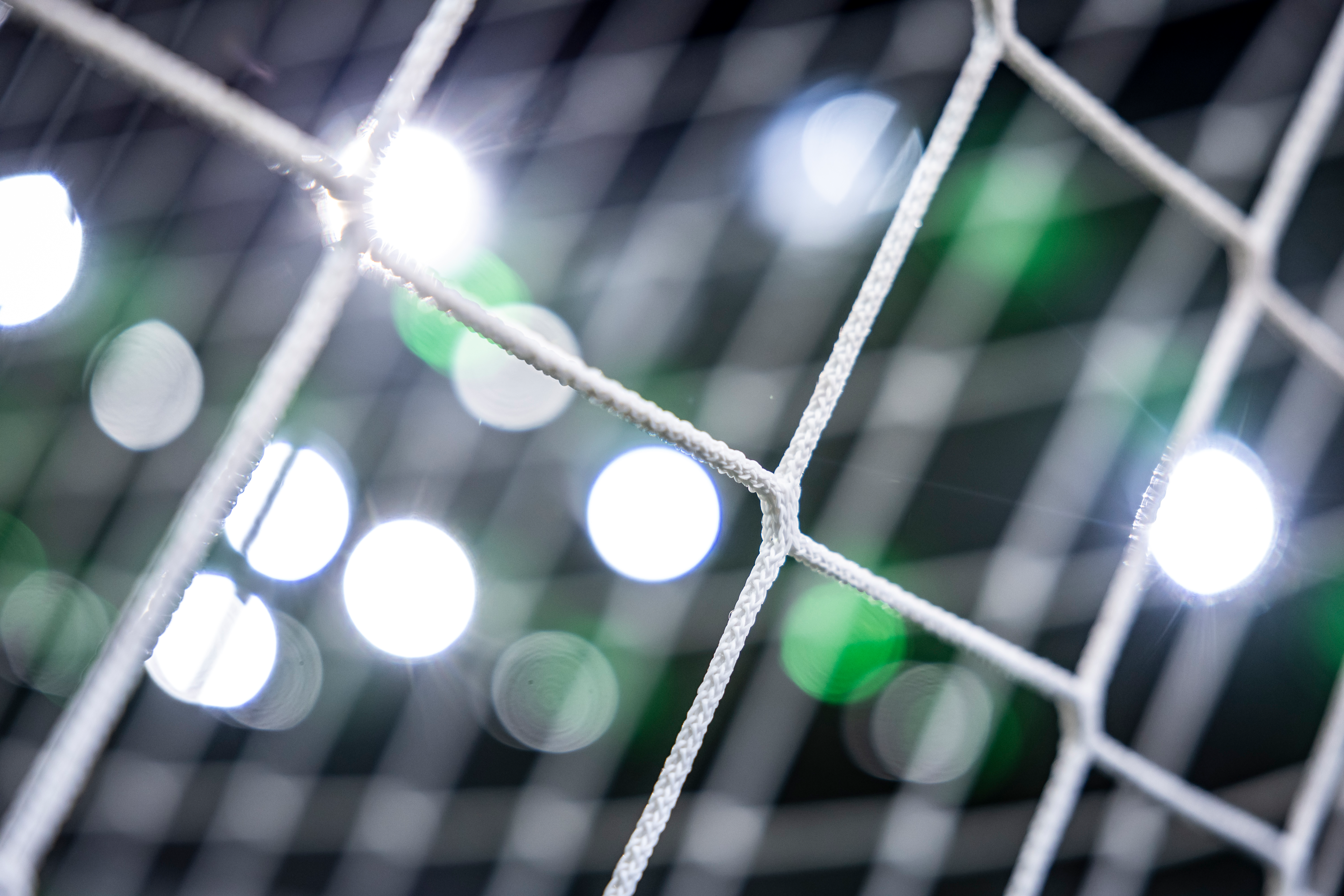 Nahaufnahme eines Tornetzes von Borussia Mönchengladbach im Stadion. Im Hintergrund sind verschwommen die Lichter der Tribüne zu sehen. 