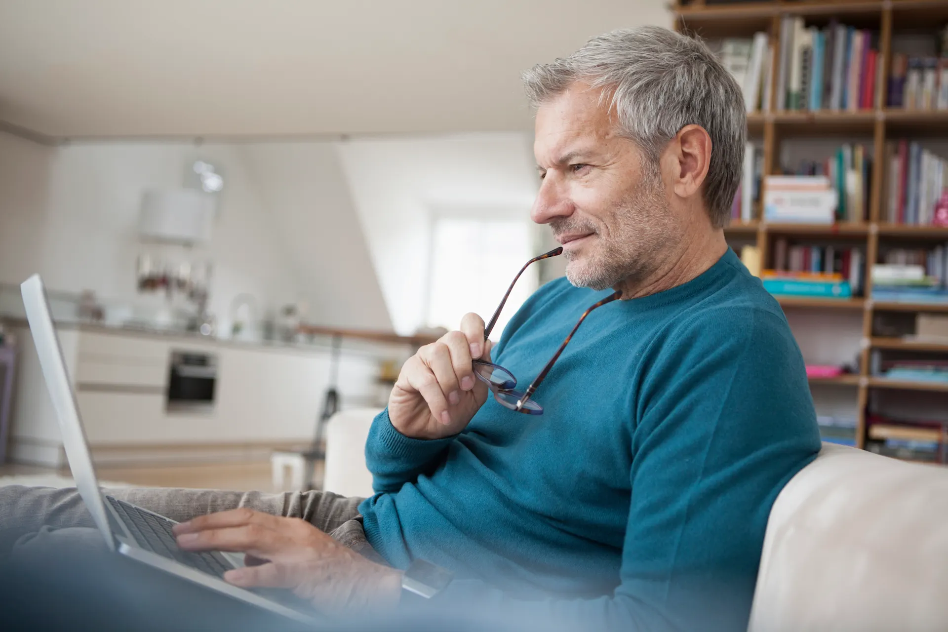 Unterlagen für Verträge suchen Mann sitzt mit seinem Laptop auf dem Sofa und schaut nach Unterlagen für Verträge von der NEW Energie.
