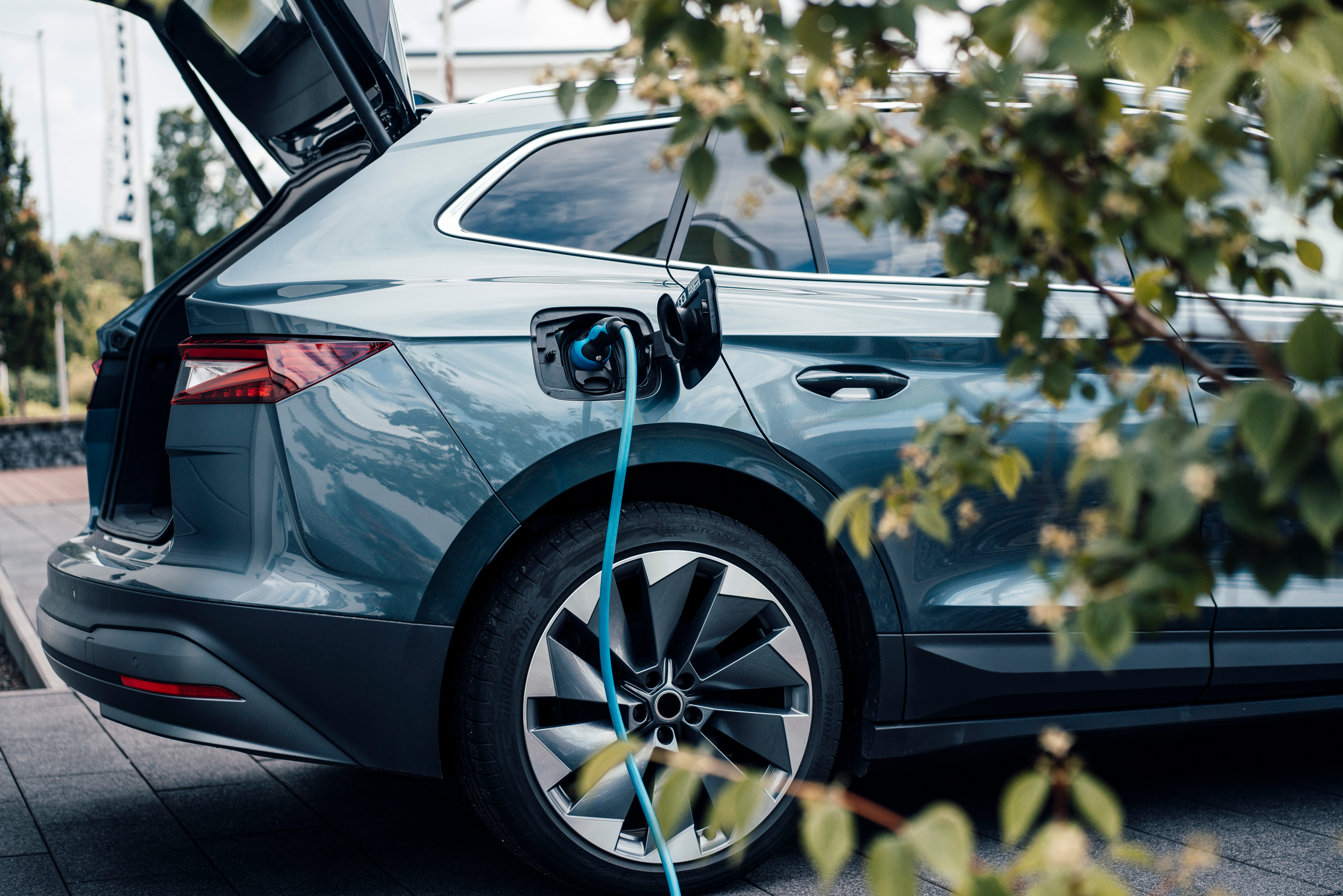 Seitenansicht eines Elektroautos während eines Ladevorgangs vor einer Garage.