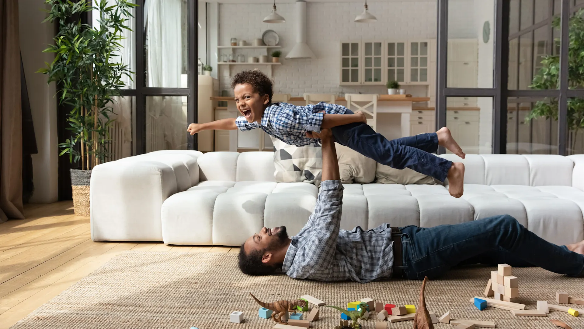 Vater und Sohn liegen auf dem Wohnzimmerboden und spielen. Die Energie kommt von NEW Energie.