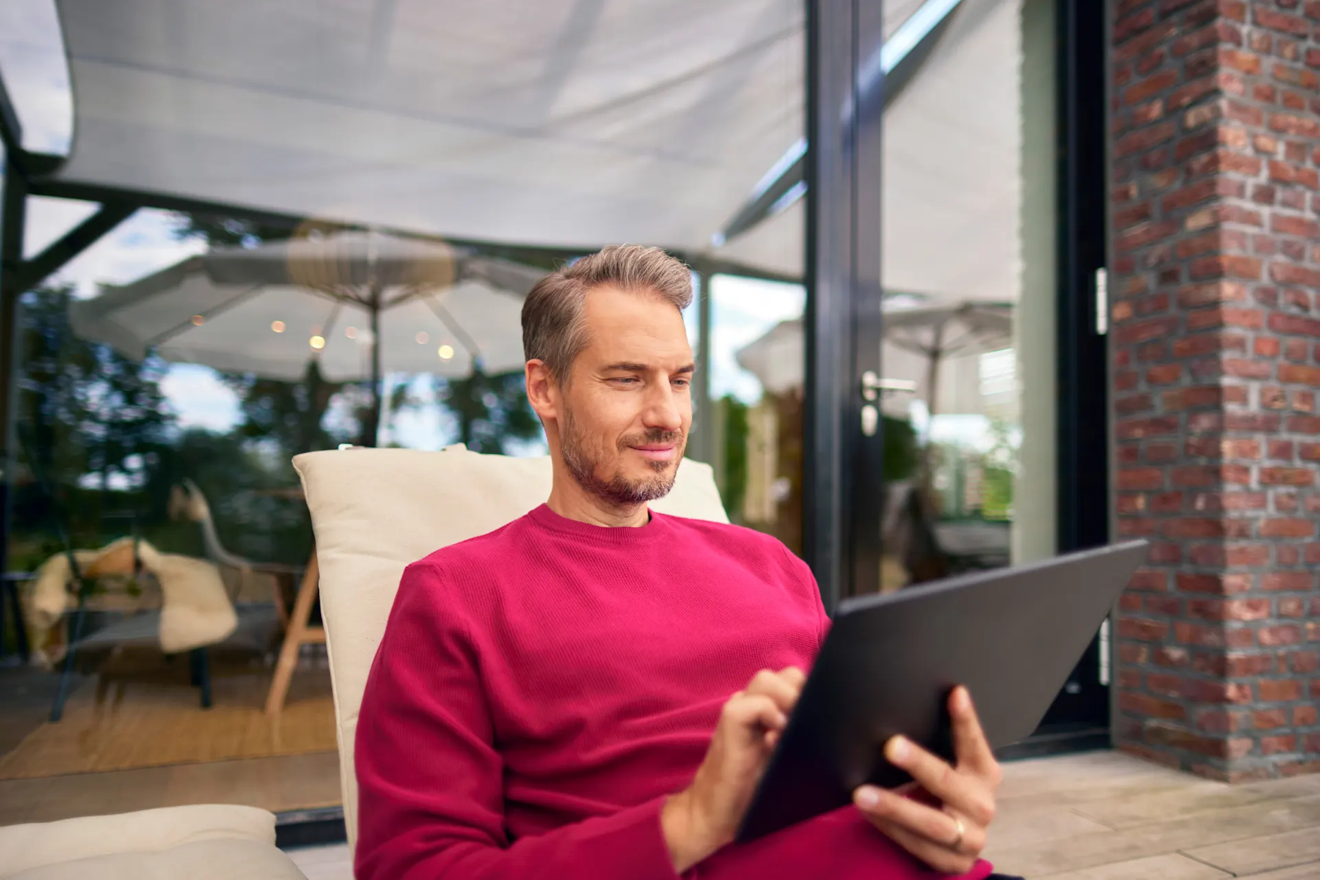Produktwelt der NEW-Energie Ein Mann sitzt auf seiner Terrasse vor seinem Haus und gibt seinen Zählerstand bei der NEW Energie durch.