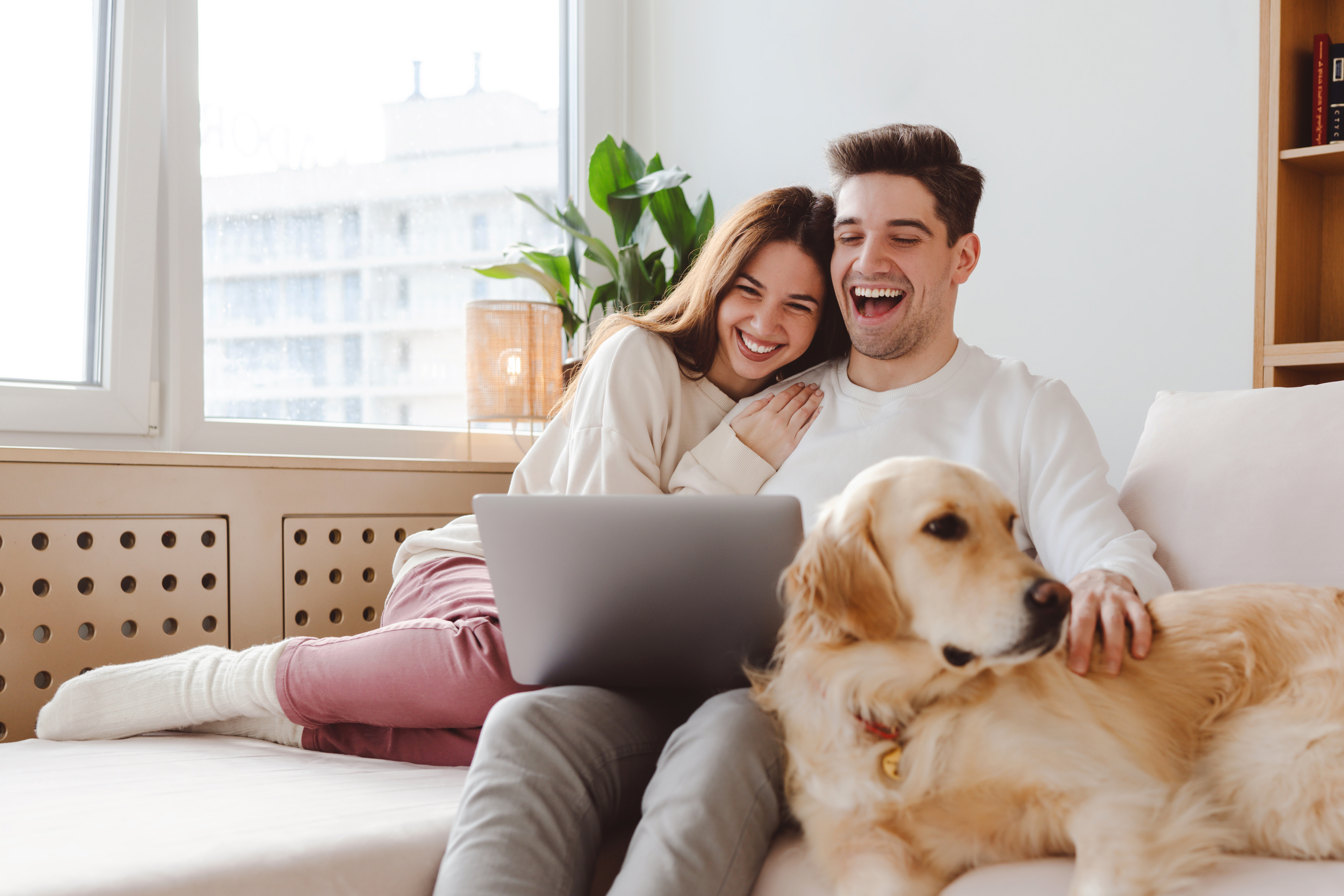 Ein Paar sitzt lächend auf dem Sofa und schauen sich die Tarife der NEW Energie an.