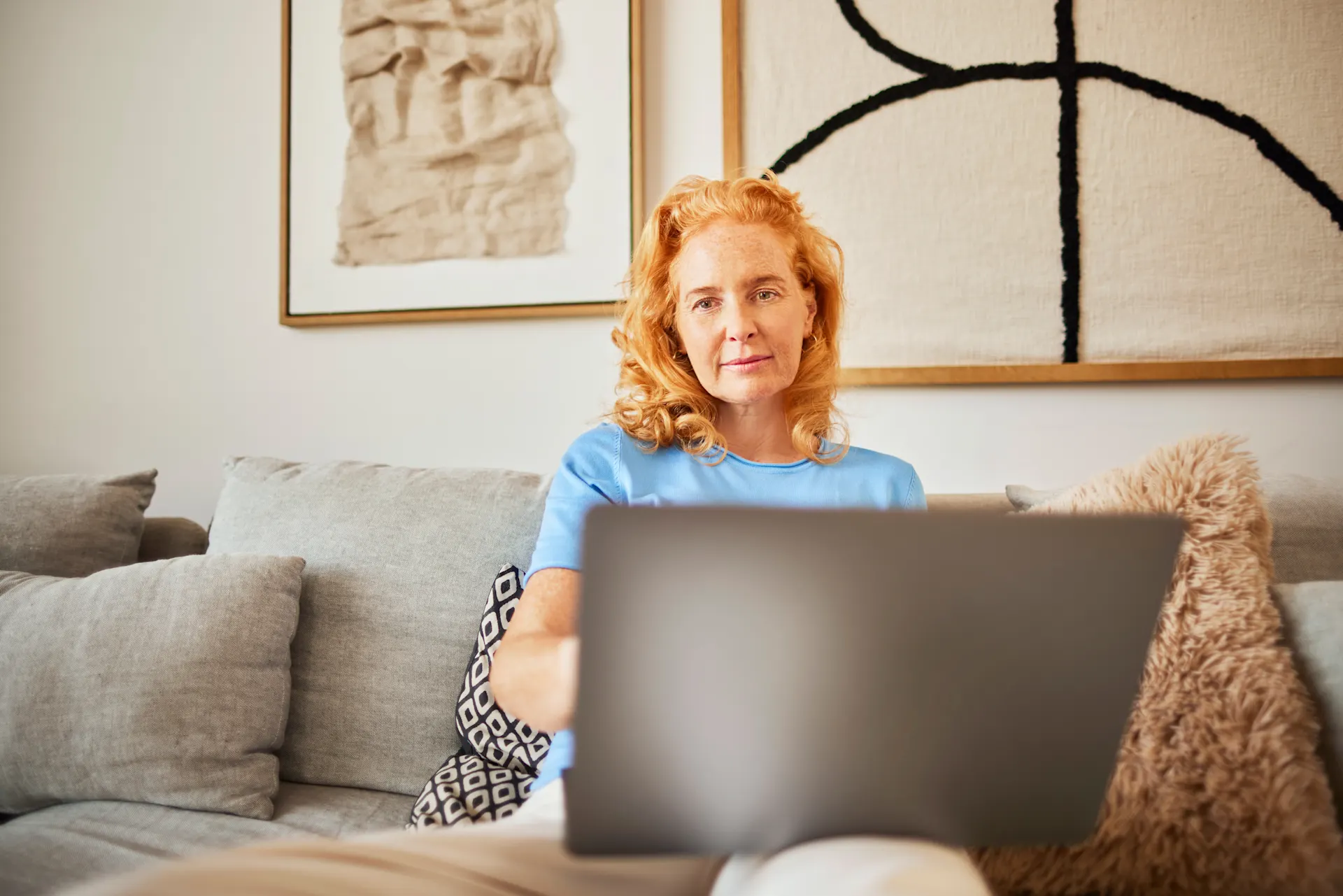 Auswahl günstiger Energie Eine Frau sitzt mit ihrem Laptop auf dem Sofa und informiert sich über die Auswahl an günstiger Energie der NEW Energie.