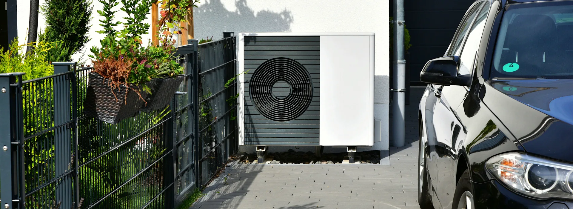Wärmepumpe an der Garage Eine Wärmepumpe steht an einer Garage im Außenbereich.