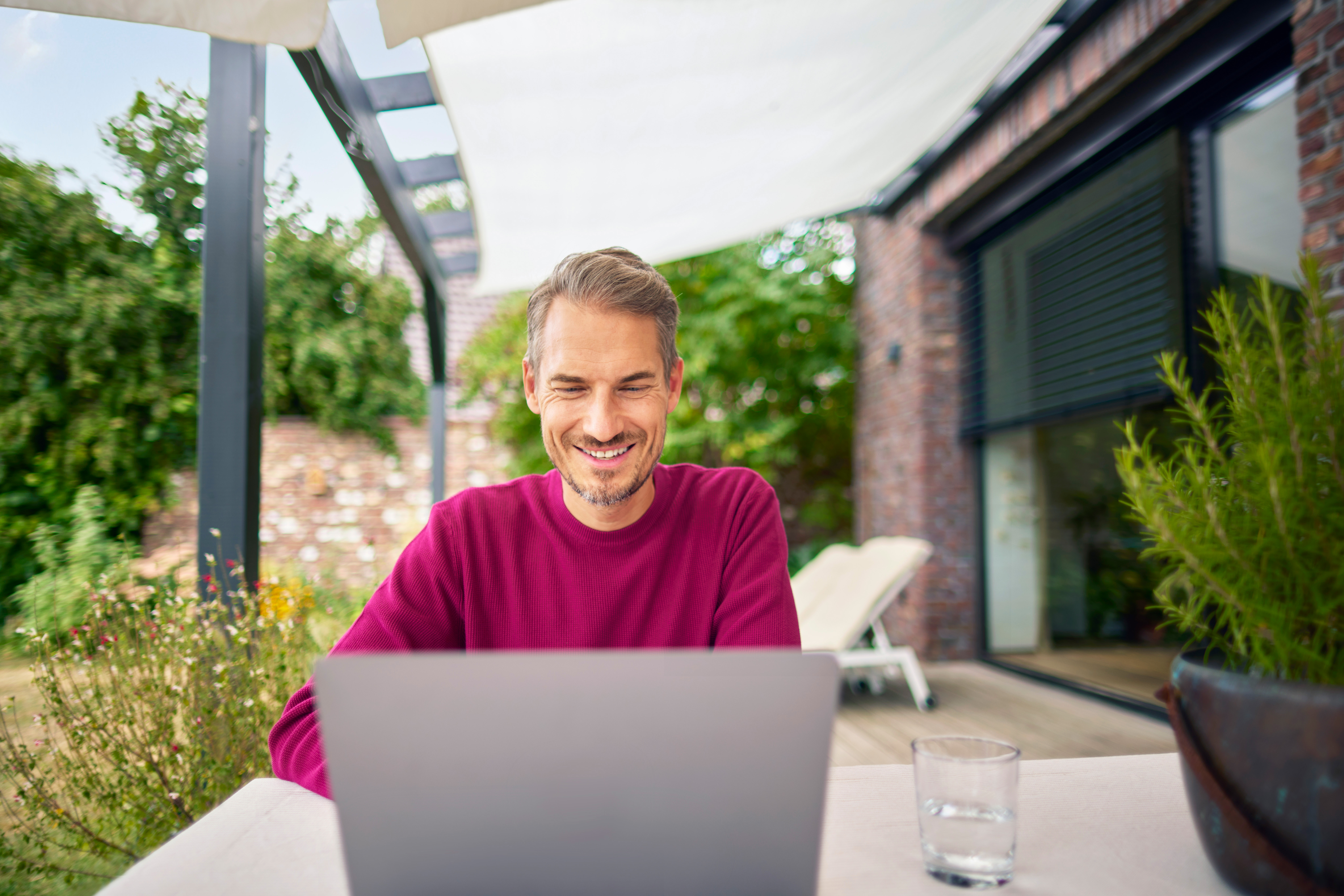 Ein Mann sitzt im Garten mit einem Laptop und informiert sich über die günstigen Tarife der NEW Energie. 