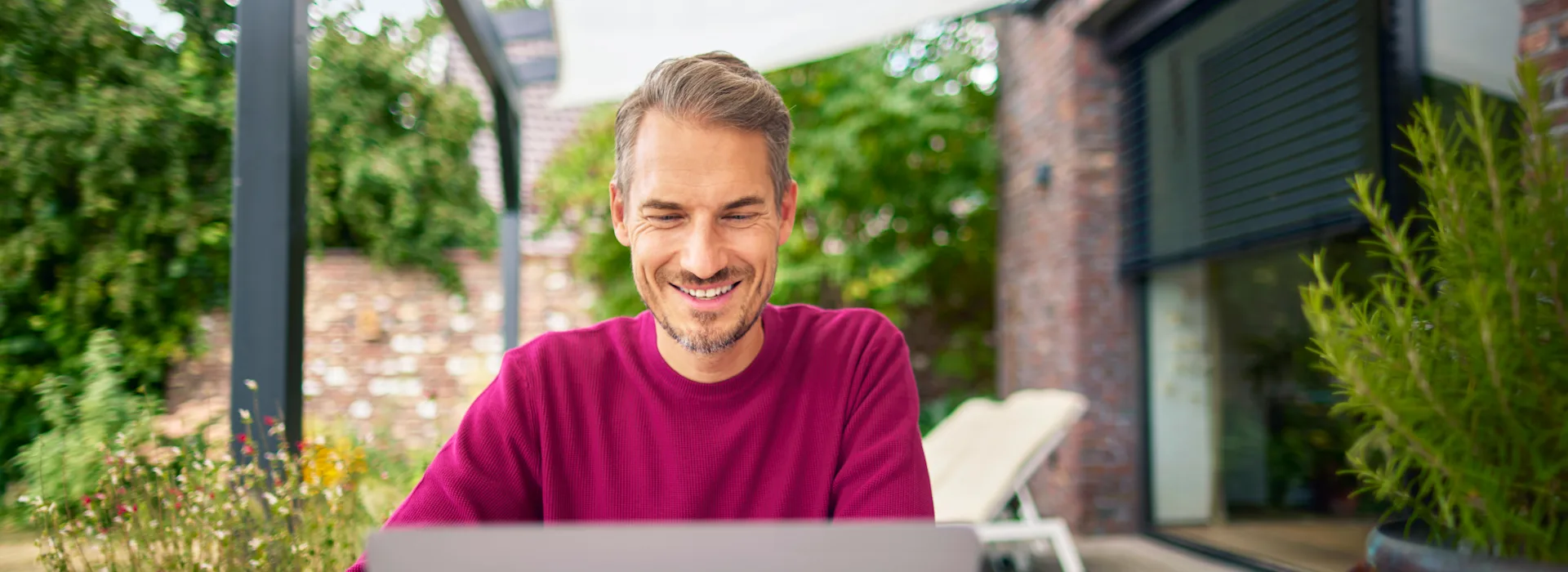 Tarifauswahl im Garten treffen Ein Mann sitzt im Garten mit einem Laptop und informiert sich über die günstigen Tarife der NEW Energie.