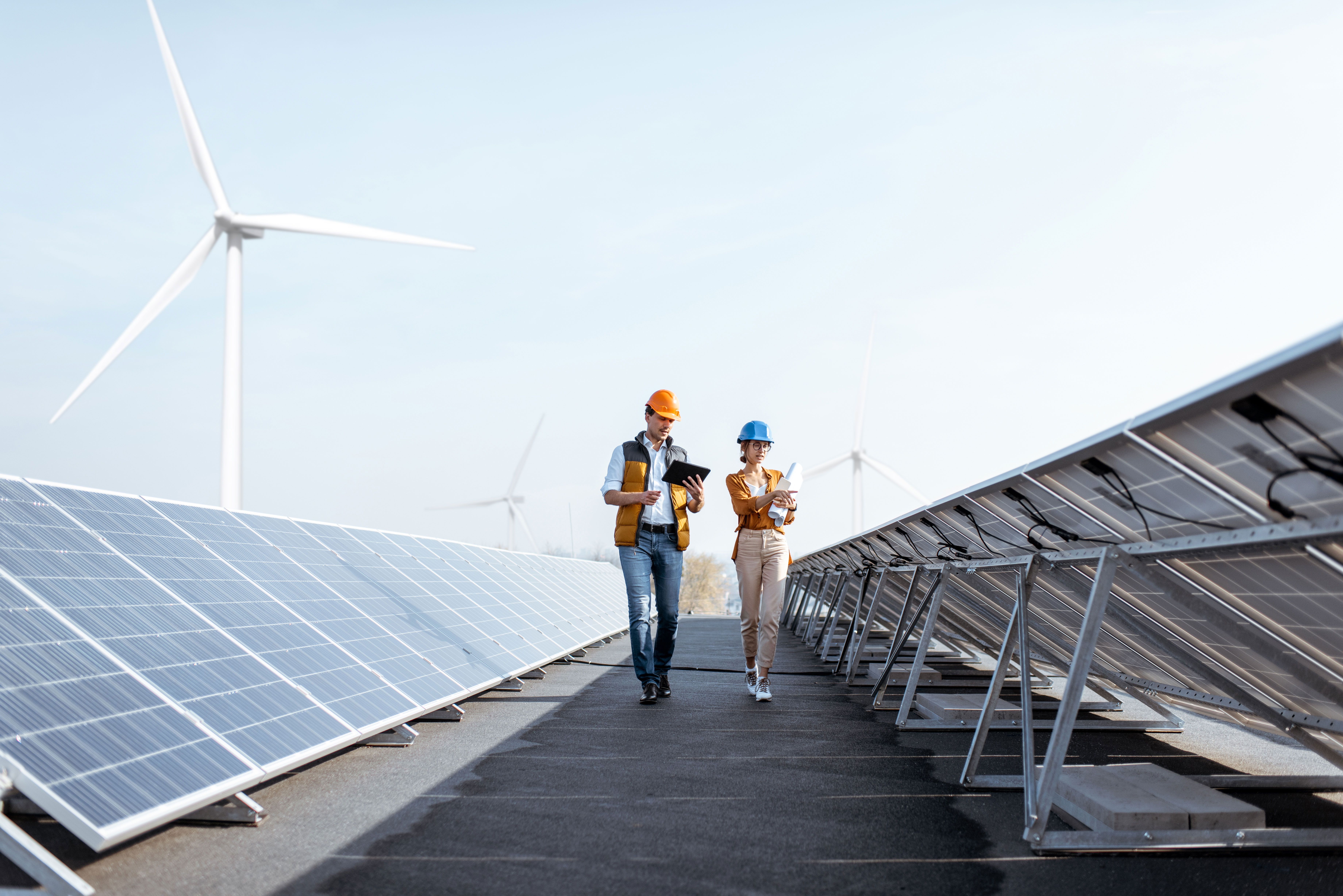 Zwei Techniker mit Sicherheitshelmen besichtigen einen Solarpark.