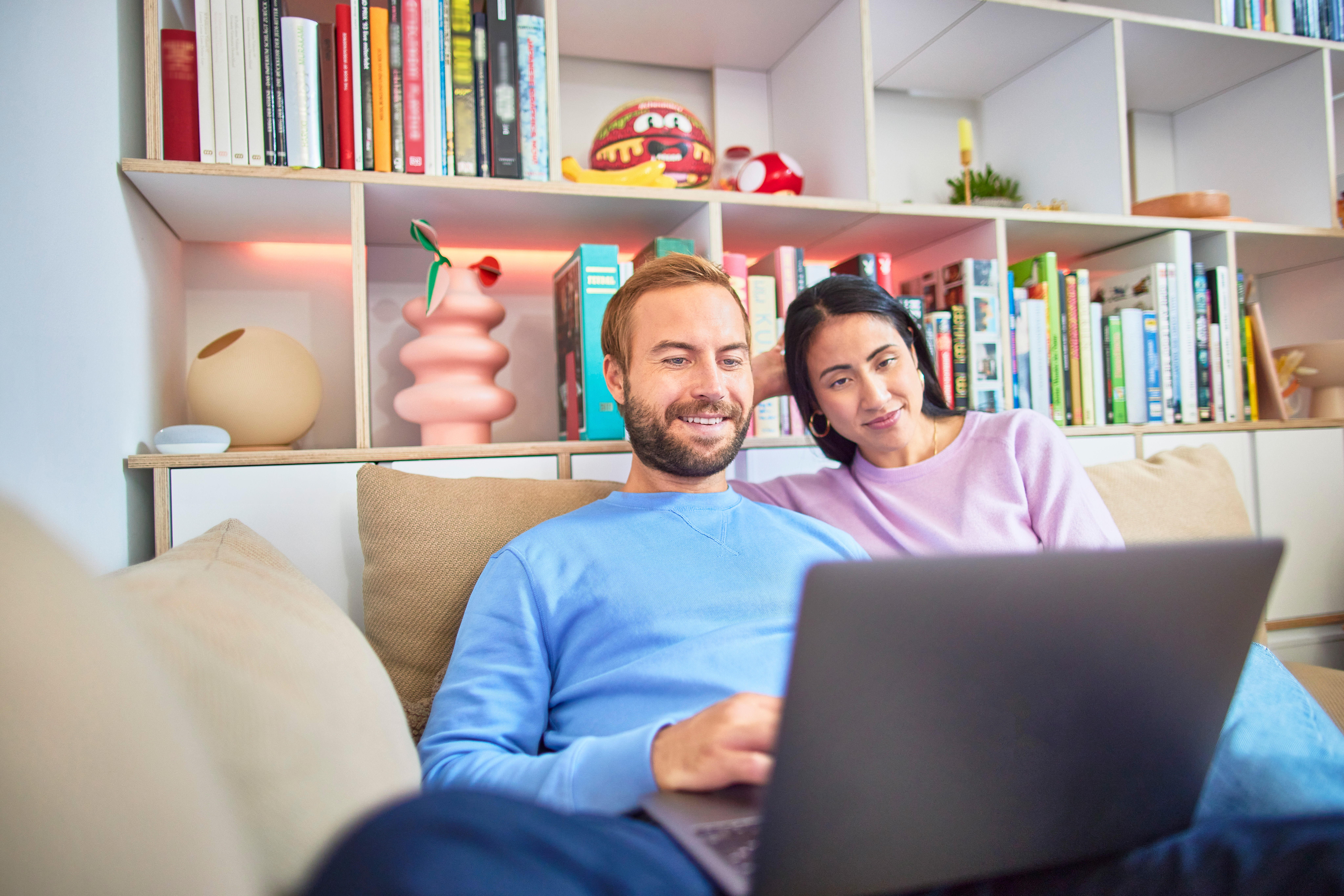 Ein Paar sitzt auf dem Sofa und vergleicht am Laptop Tarife der NEW Energie.