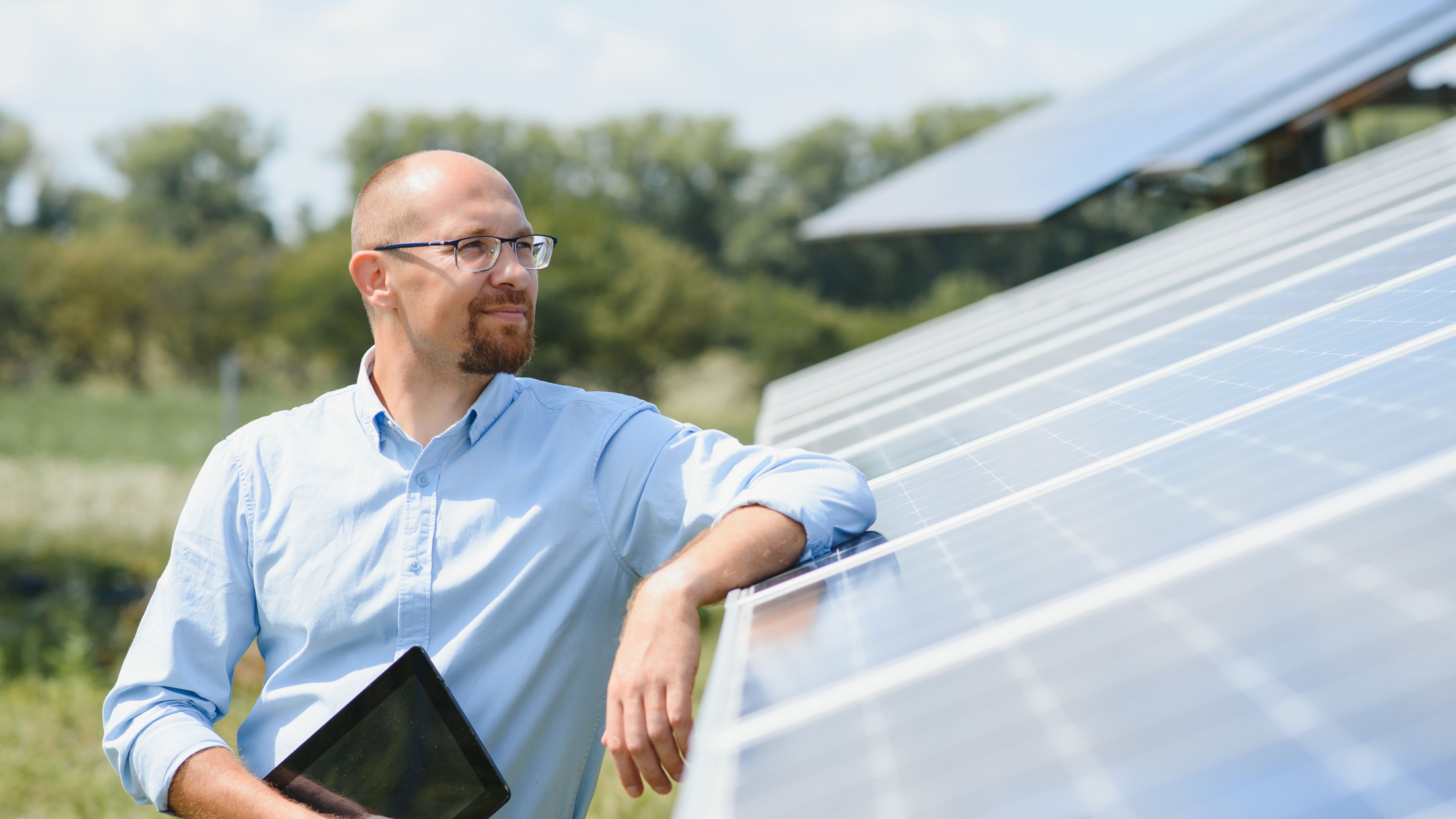 Ein Mann steht draußen neben einer großen Photovoltaikanlage der NEW Energie.