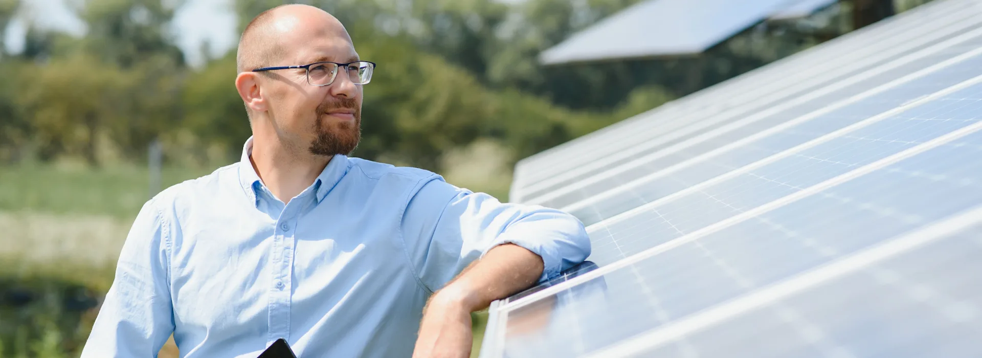 Mann steht vor großer PV-Anlage Ein Mann steht draußen neben einer großen Photovoltaikanlage der NEW Energie.