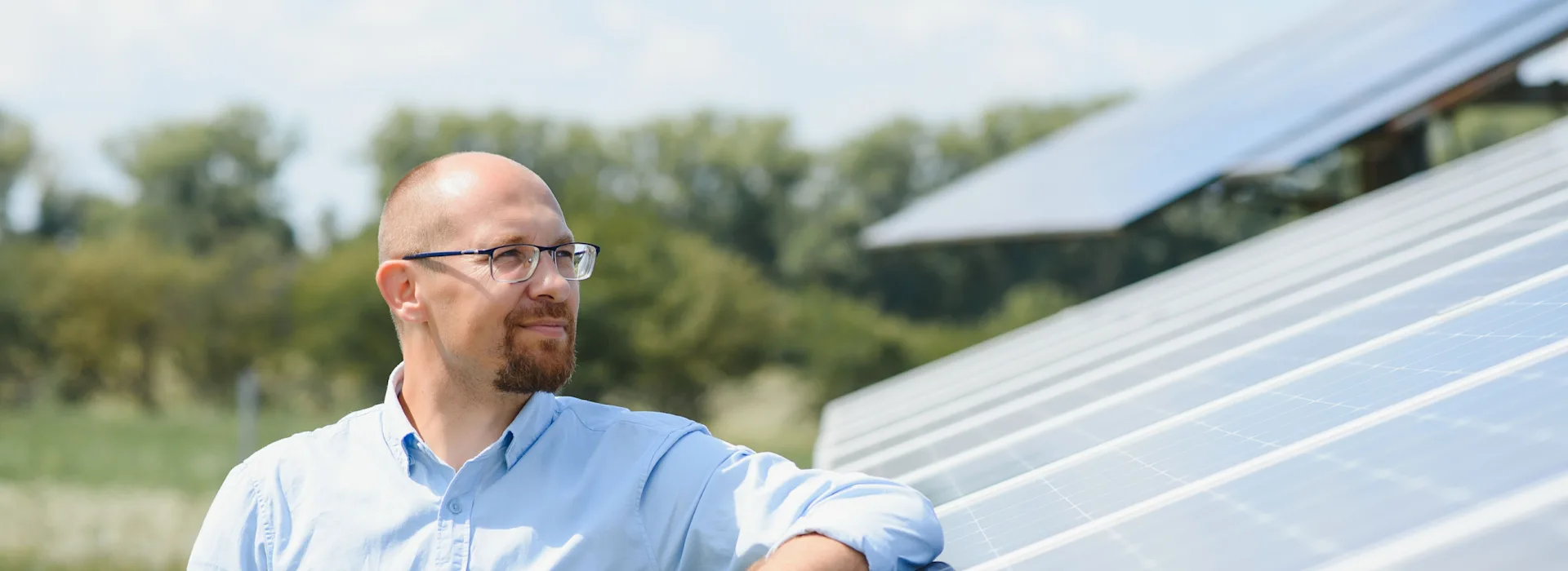 Mann steht vor großer PV-Anlage Ein Mann steht draußen neben einer großen Photovoltaikanlage der NEW Energie.