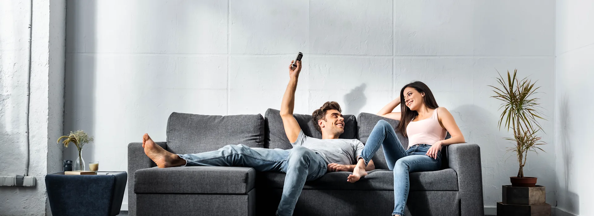Luft-Luft Wärmepumpe Zwei Personen sitzen im Wohnzimmer auf einem dunklem Sofa und nutzen energieeffiziente Technik – mit Strom von NEW Energie.