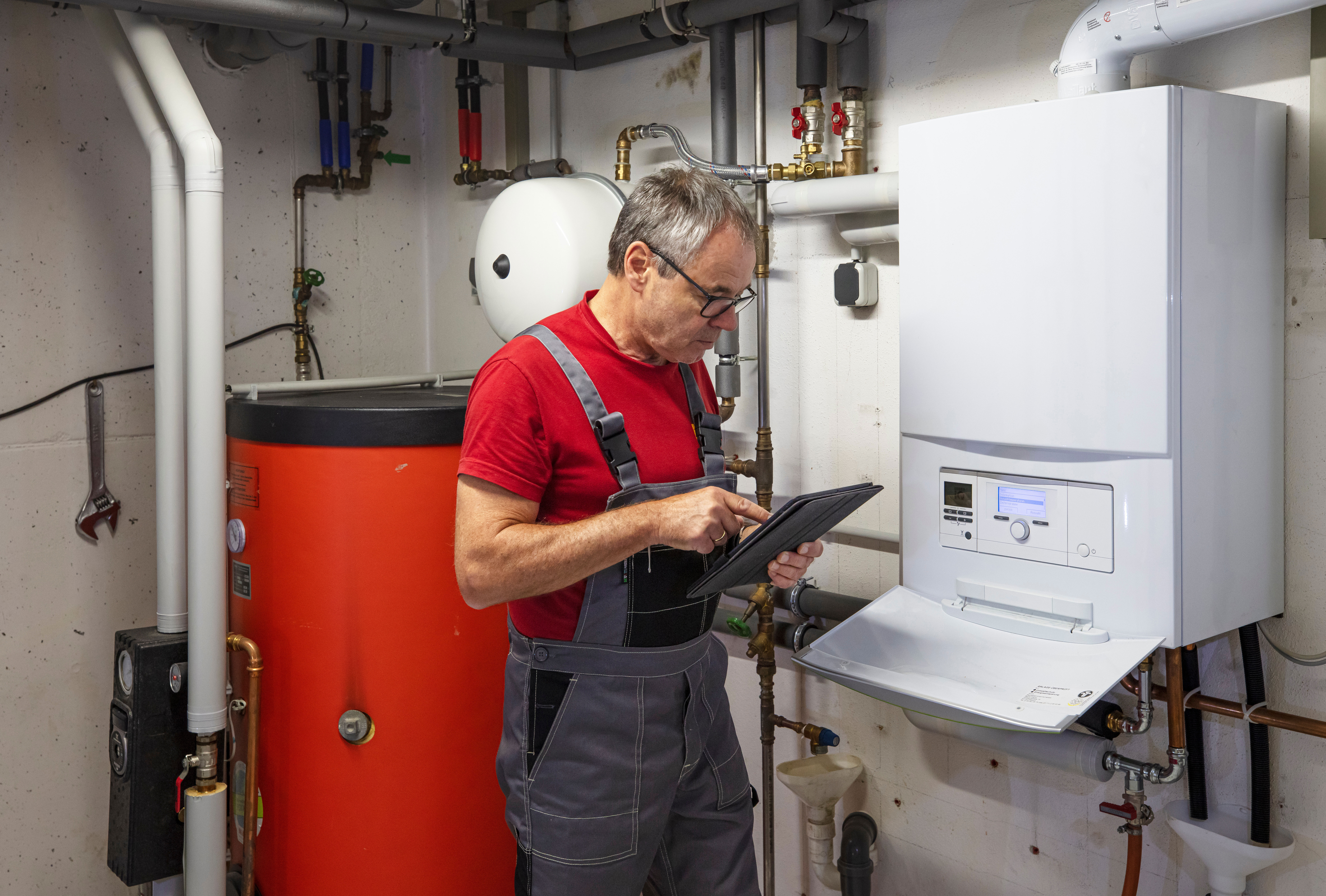 Ein Heizungsmonteur steht an einer Heizungsanlage der NEW Energie und führt seine Arbeit durch.