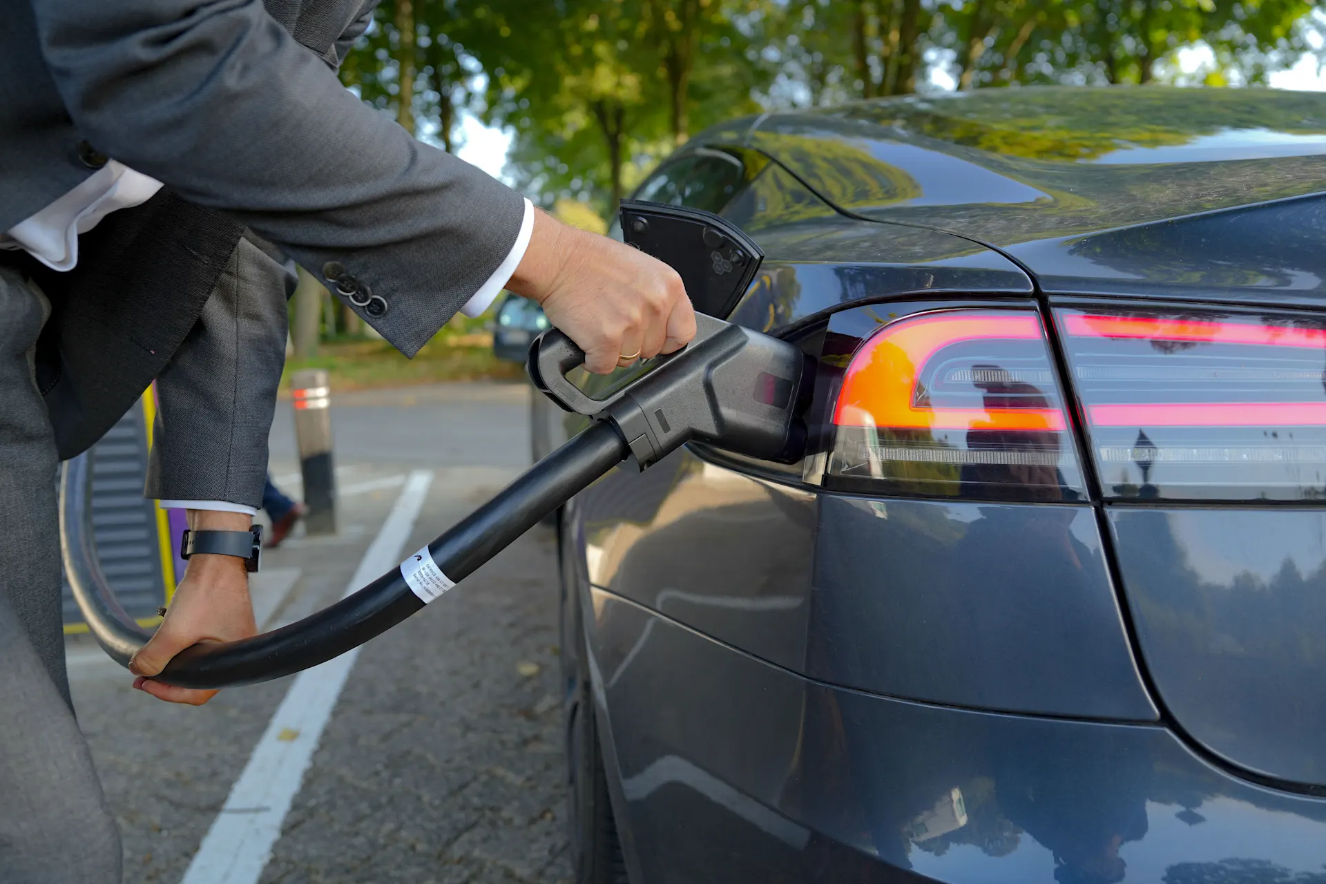 E-Auto am Stecker Ein Mann im Anzug lädt sein E-Auto an einer Ladesäule der NEW Energie.
