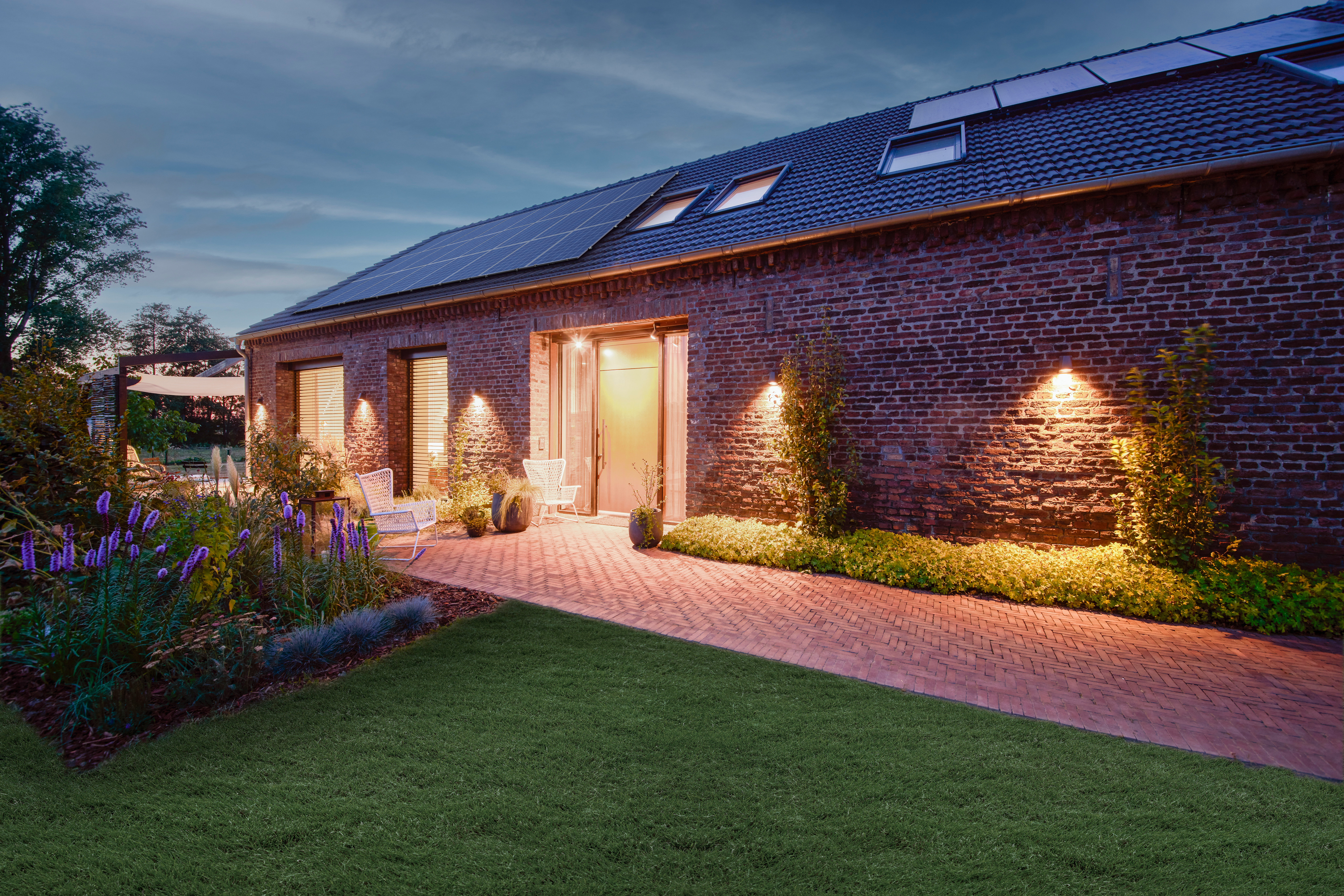 Ein Haus mit einem Energie Dach von der NEW Energie, wird am Abend mit Ökostrom, erzeugt durch eine Photovoltaik Anlage, betrieben.