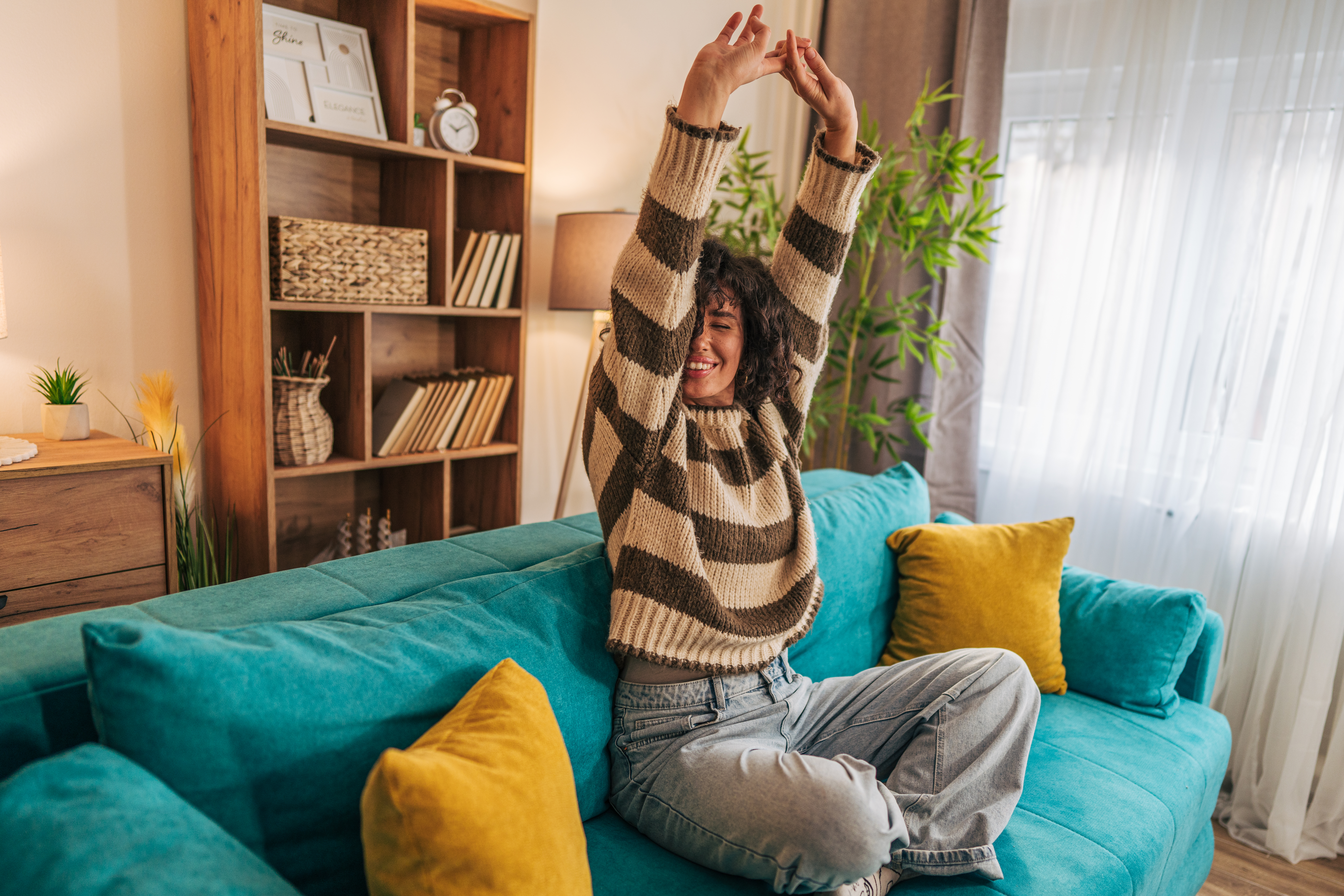 Frau sitzt lachend auf dem Sofa und streckt sich. Sie freut sich über den günstigen Gastarif für 2027.