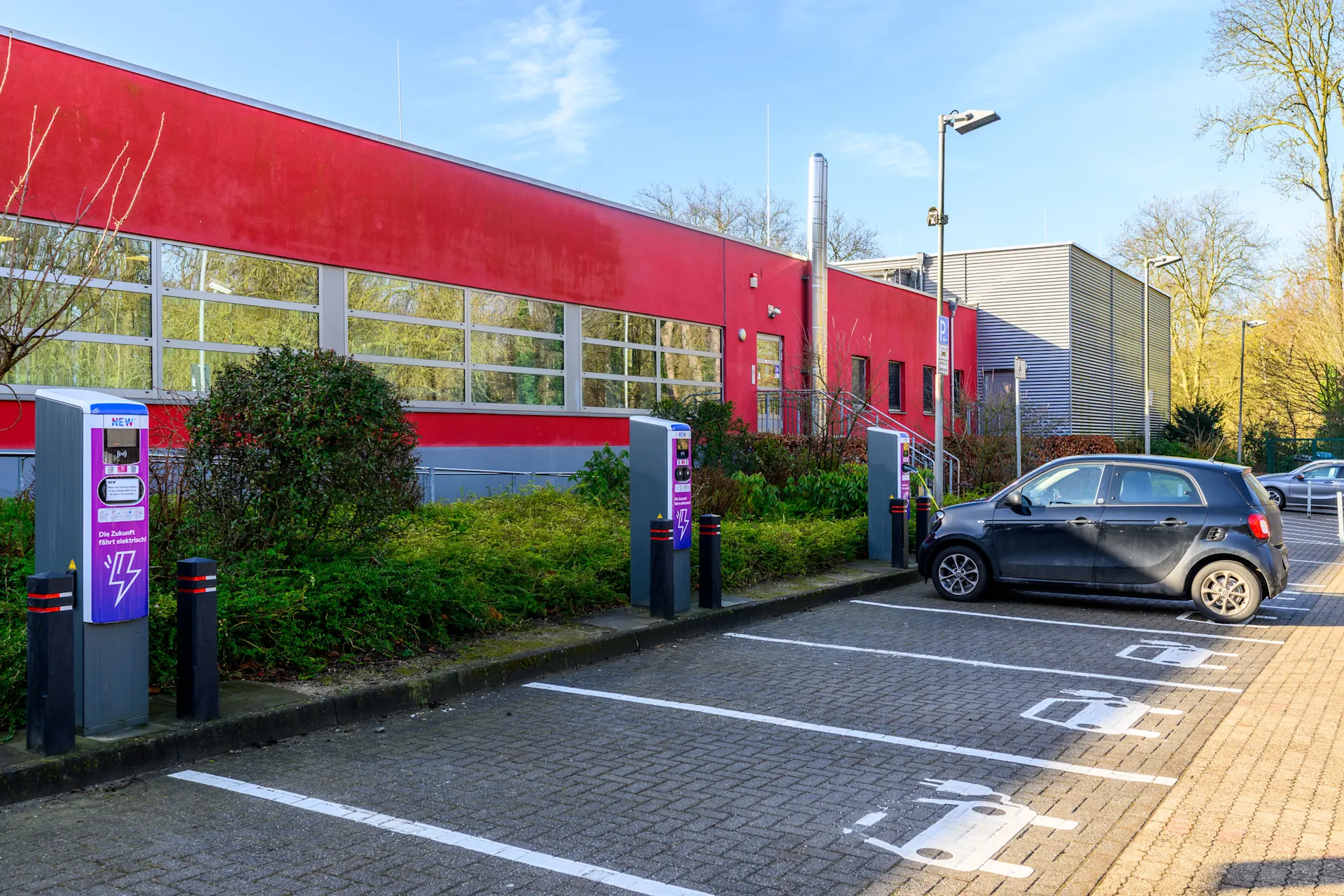Auf dem Parkplatz des Schlossbads Niederrhein stehen mehrere Ladesäuen der NEW Energie. 