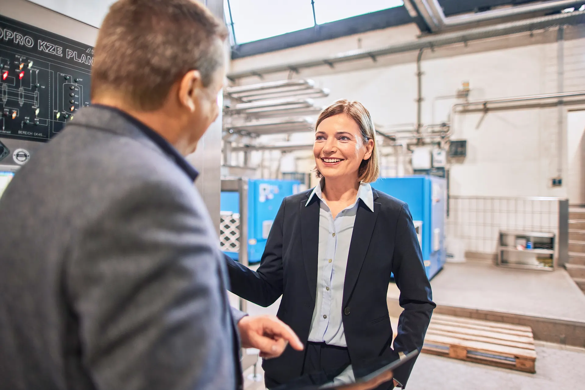 Kundenberatung über ein Energieaudit Eine Geschäftsführerin steht mit einem Mitarbeiter der NEW in der Produktionshalle an einem Schaltkasten.