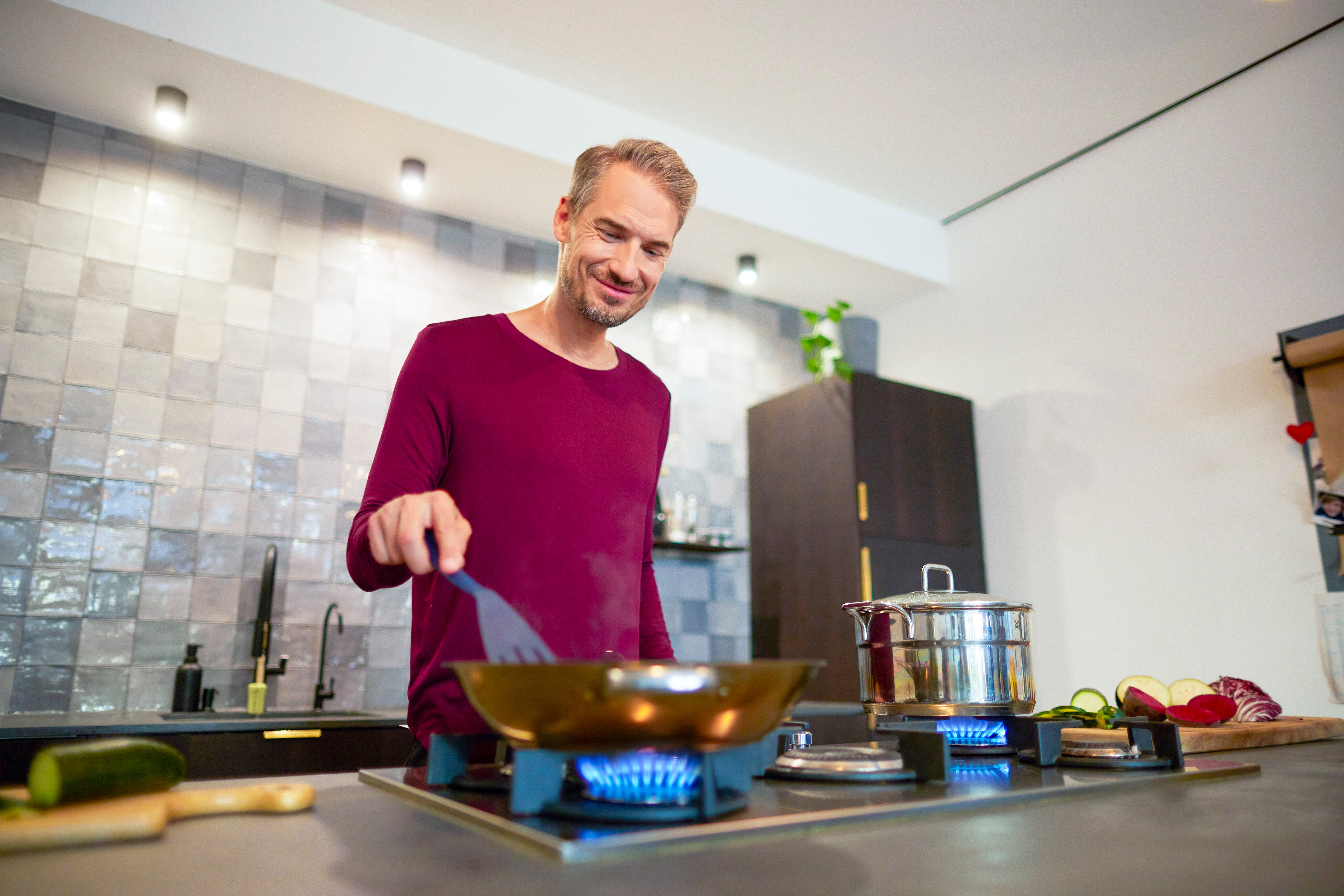 Ein Mann bereitet das Abendessen auf einem Gasherd vor, welcher durch Gas der NEW Energie betrieben wird.