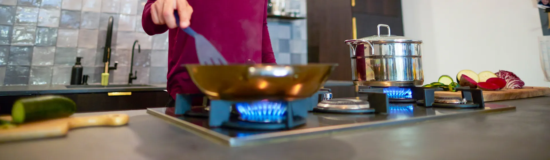 Abendessen zubereiten mit der NEW Energie Ein Mann bereitet das Abendessen auf einem Gasherd vor, welcher durch Gas der NEW Energie betrieben wird.
