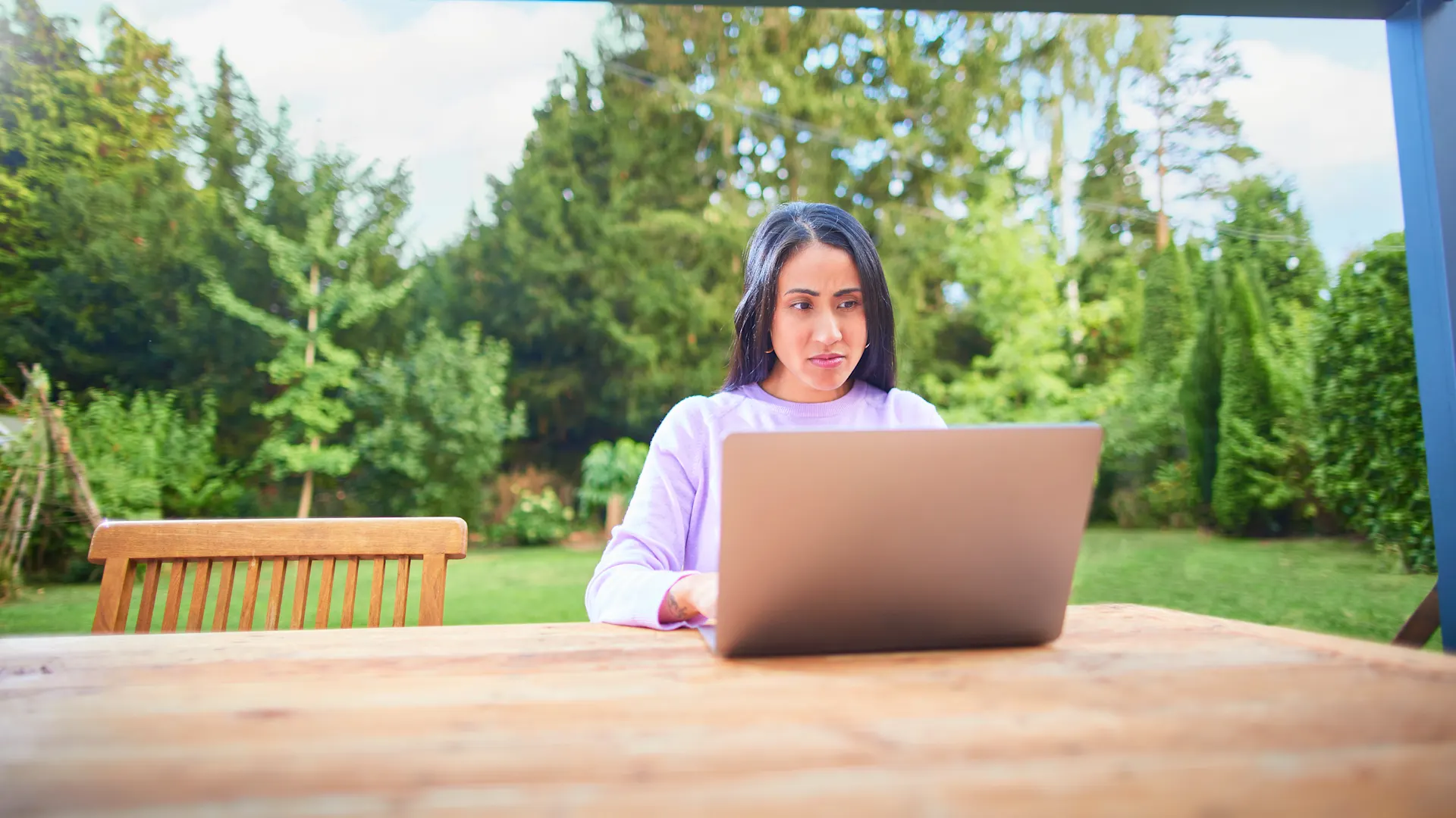 Frau am Laptop bearbeitet Ihren Tarif Eine Frau sitzt mit einem Laptop im Garten und informiert sich über die NEW Energie.