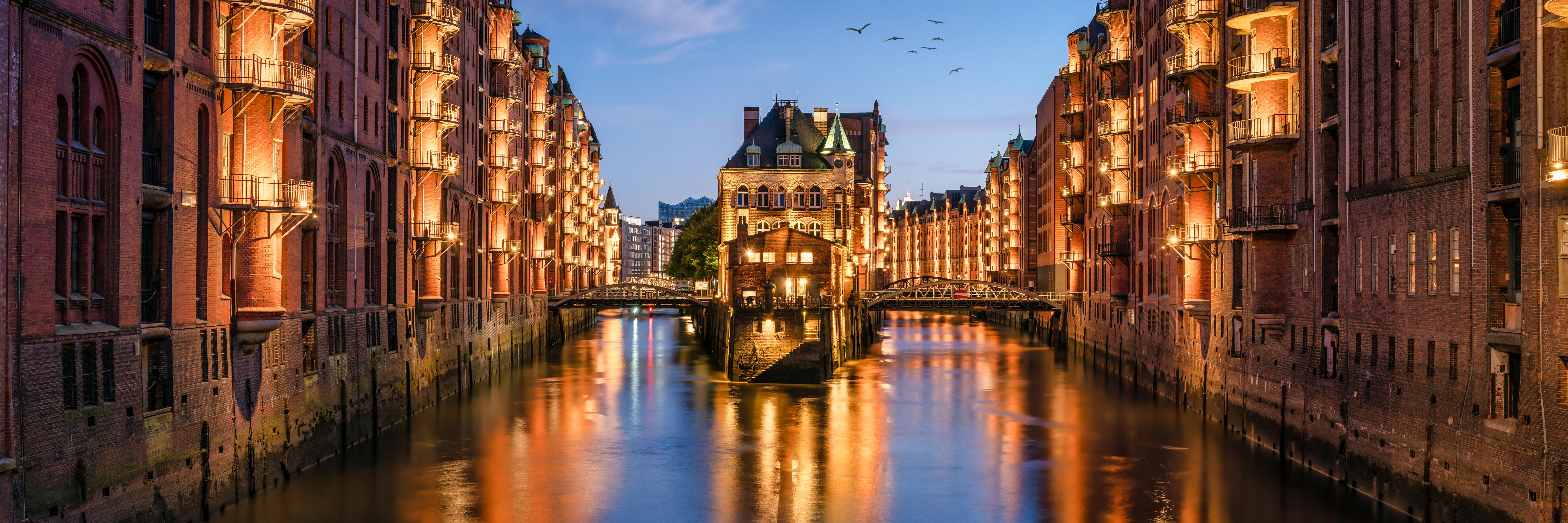 Hamburger Speicherstadt am Abend mit Blick auf das Wasser. Speicherstadt ist beleuchtet. Strom von NEW Energie.