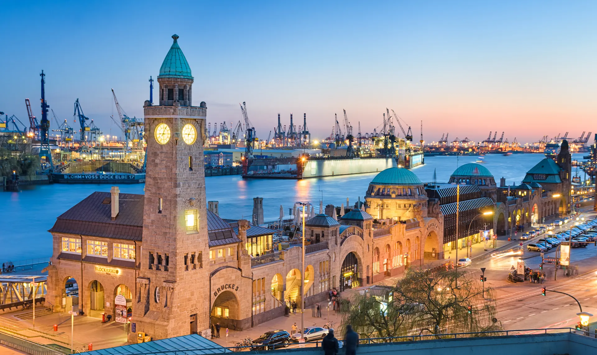 Strom für Hamburg von der NEW Energie Blick auf die Landungsbrücken und Hafen von Hamburg am Abend. Alles ist beleuchtet. Strom von der NEW Energie.