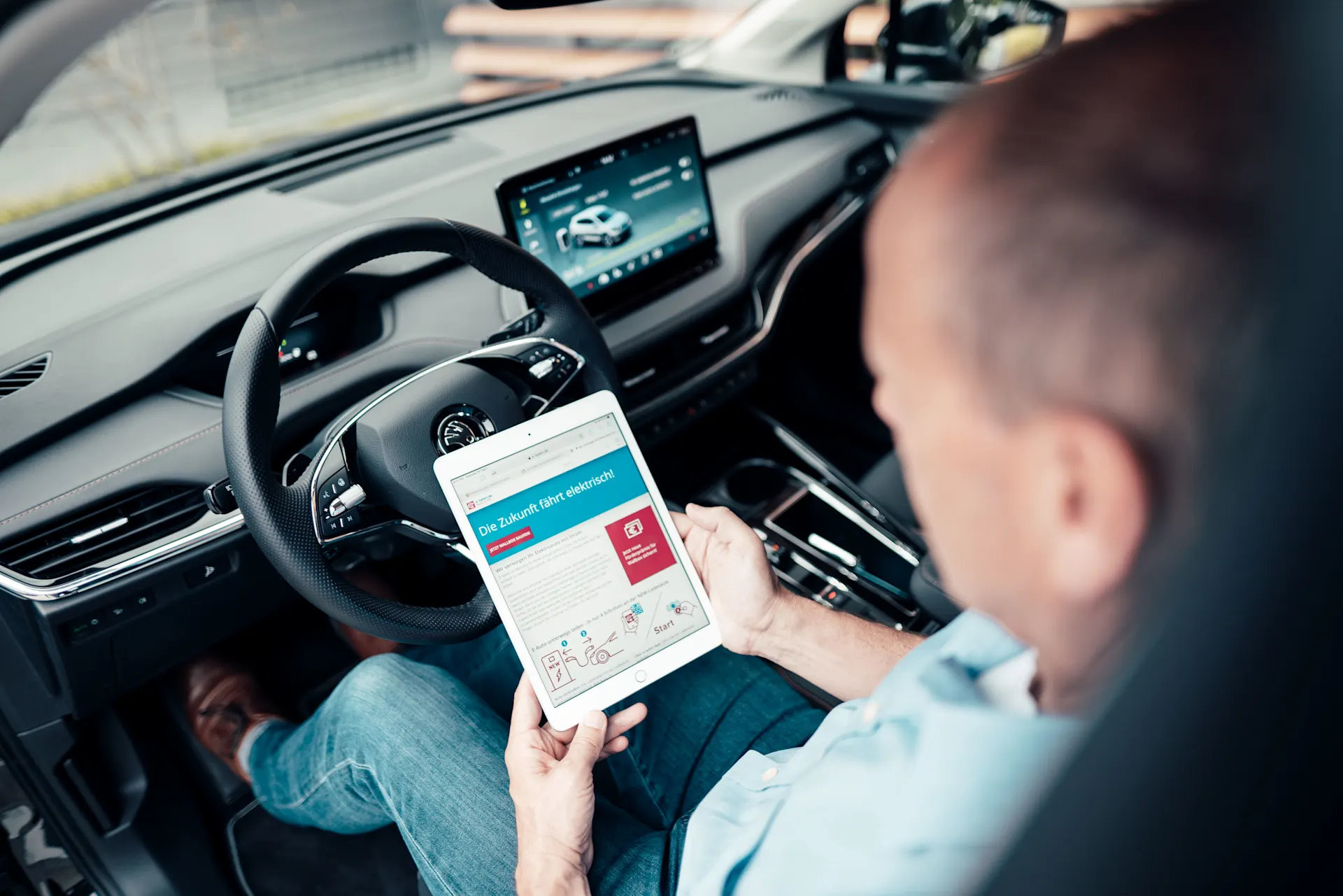 Ein Mann sitzt im E-Auto und informiert sich bei der NEW Energie über Autostromtarife.