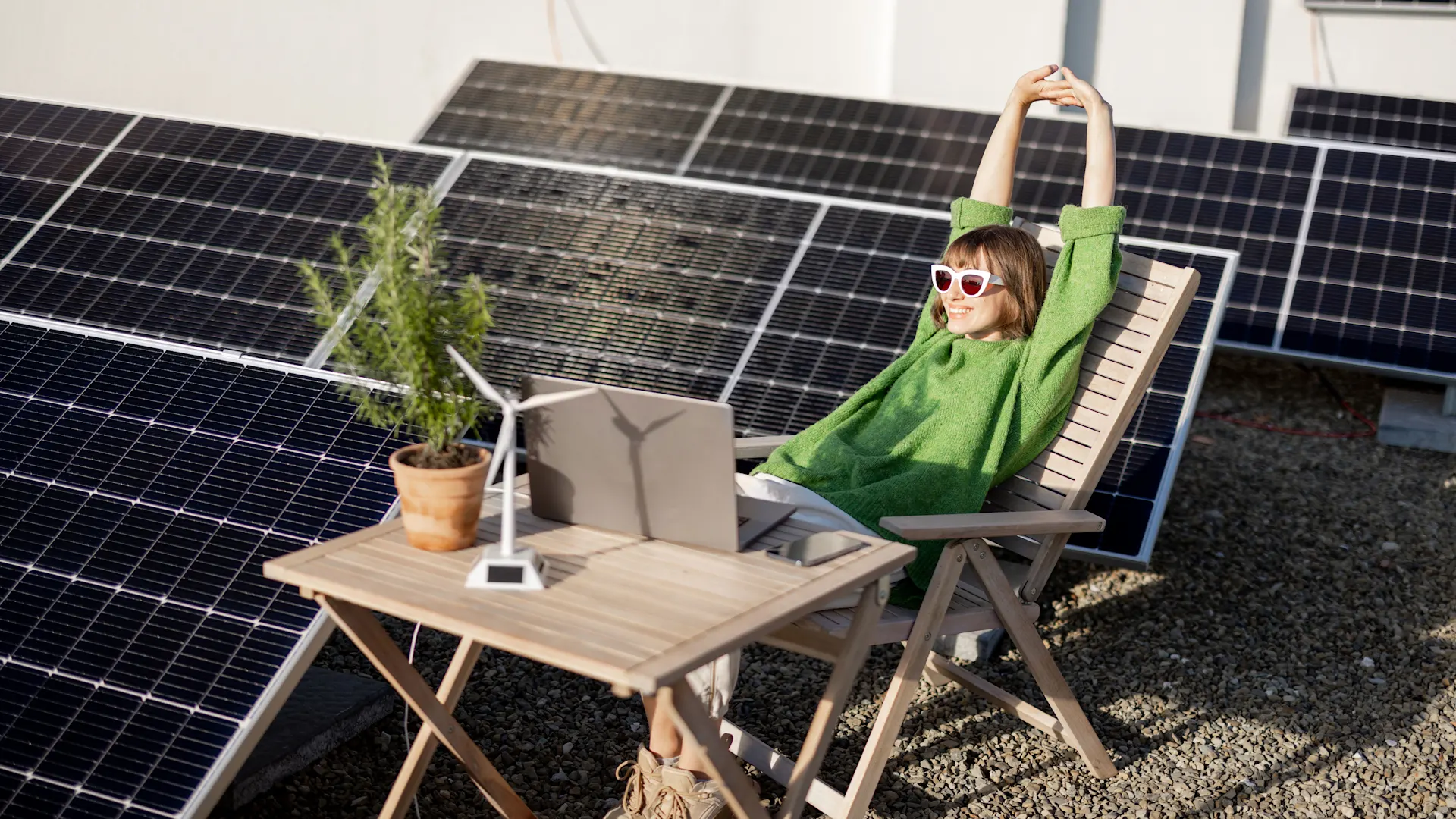 Strom selber erzeugen Die Frau sitzt neben einer Photovoltaikanlage der NEW Energie auf dem Dach.