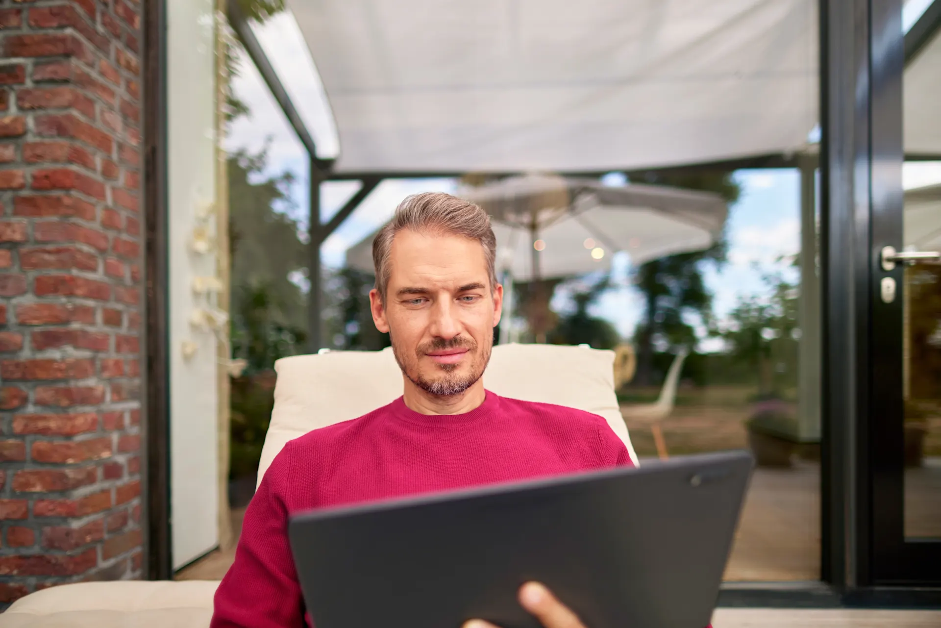 Wissenswertes und Neuigkeiten Ein Mann auf einer Gartenliege schaut sich mit einem Tablet alles Wissenswertes über die Energietarife bei der NEW Energie an.