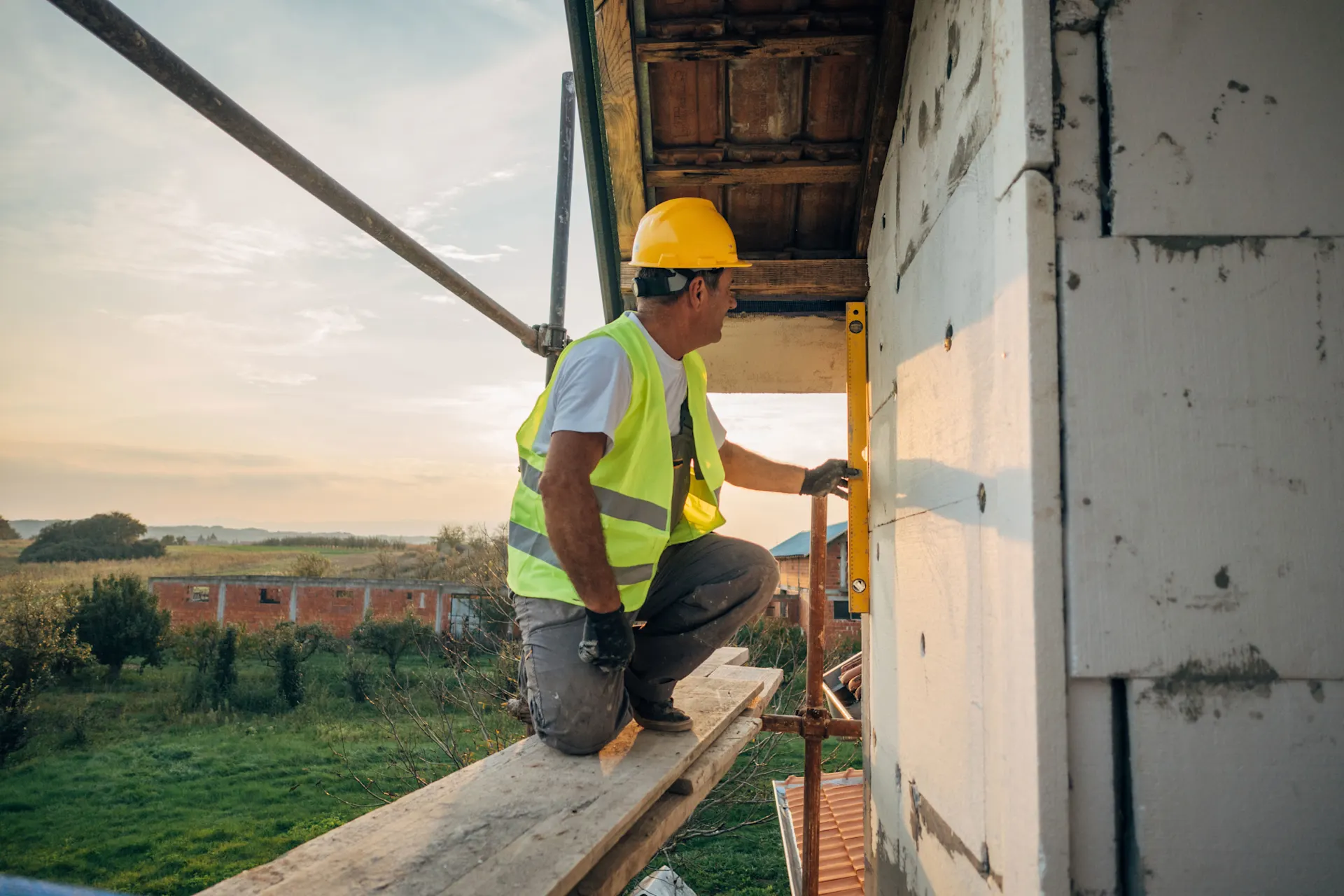 Arbeiten an der Hauswand Ein Arbeiter arbeitet zur Verbesserung der Energieeffizienz an einer Hauswand.