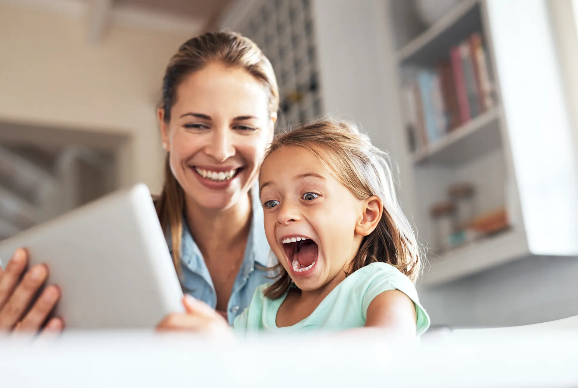 Frau Mit Kind am Tablet Eine Frau sitzt mit einem Kind vor einem Tablet und sie freuen sich über attraktive Tarife der NEW Energie.