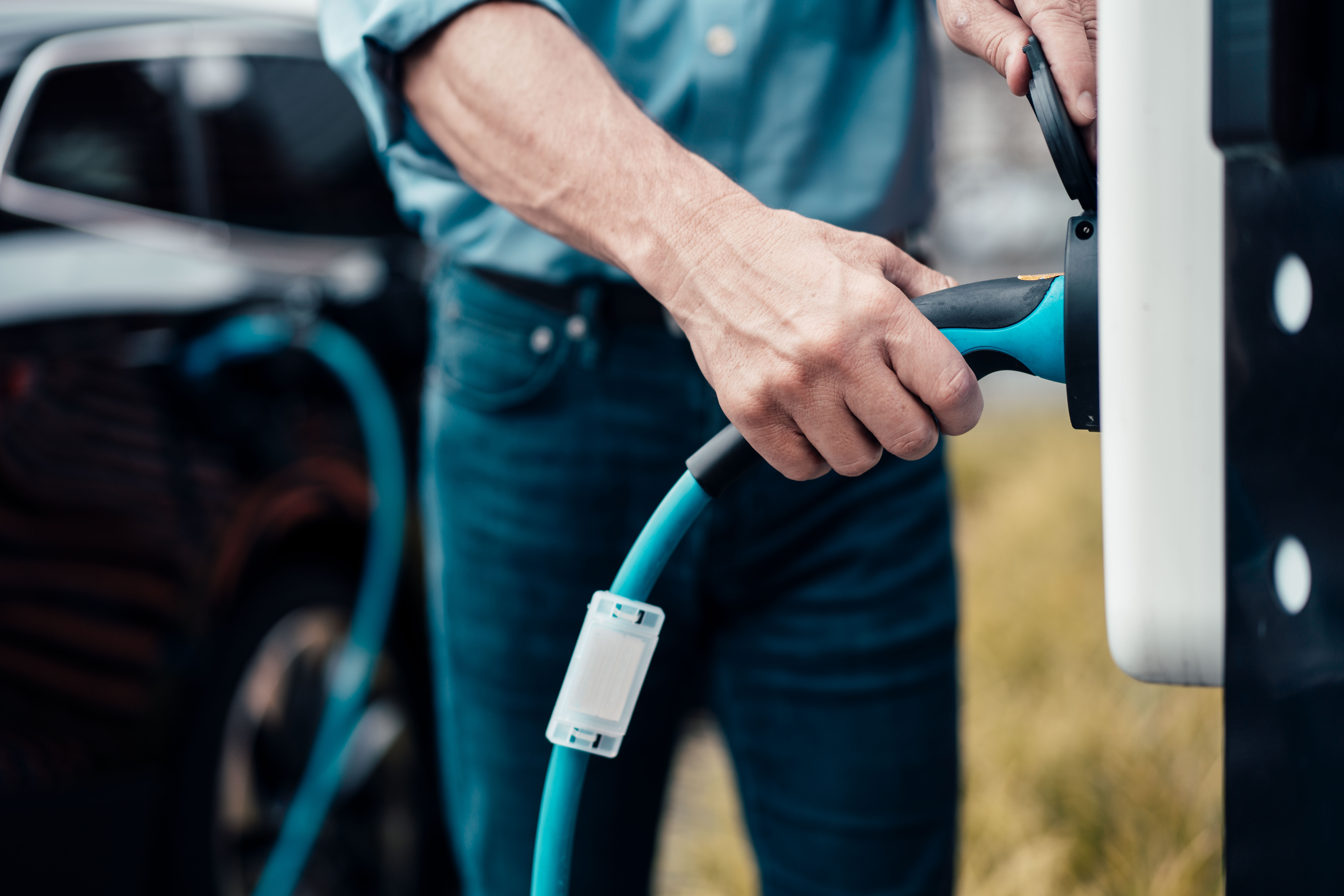 Das Ladekabel wir von einem Mann in die Wallbox gesteckt und das Auto wird mit Autostrom der NEW Energie geladen.