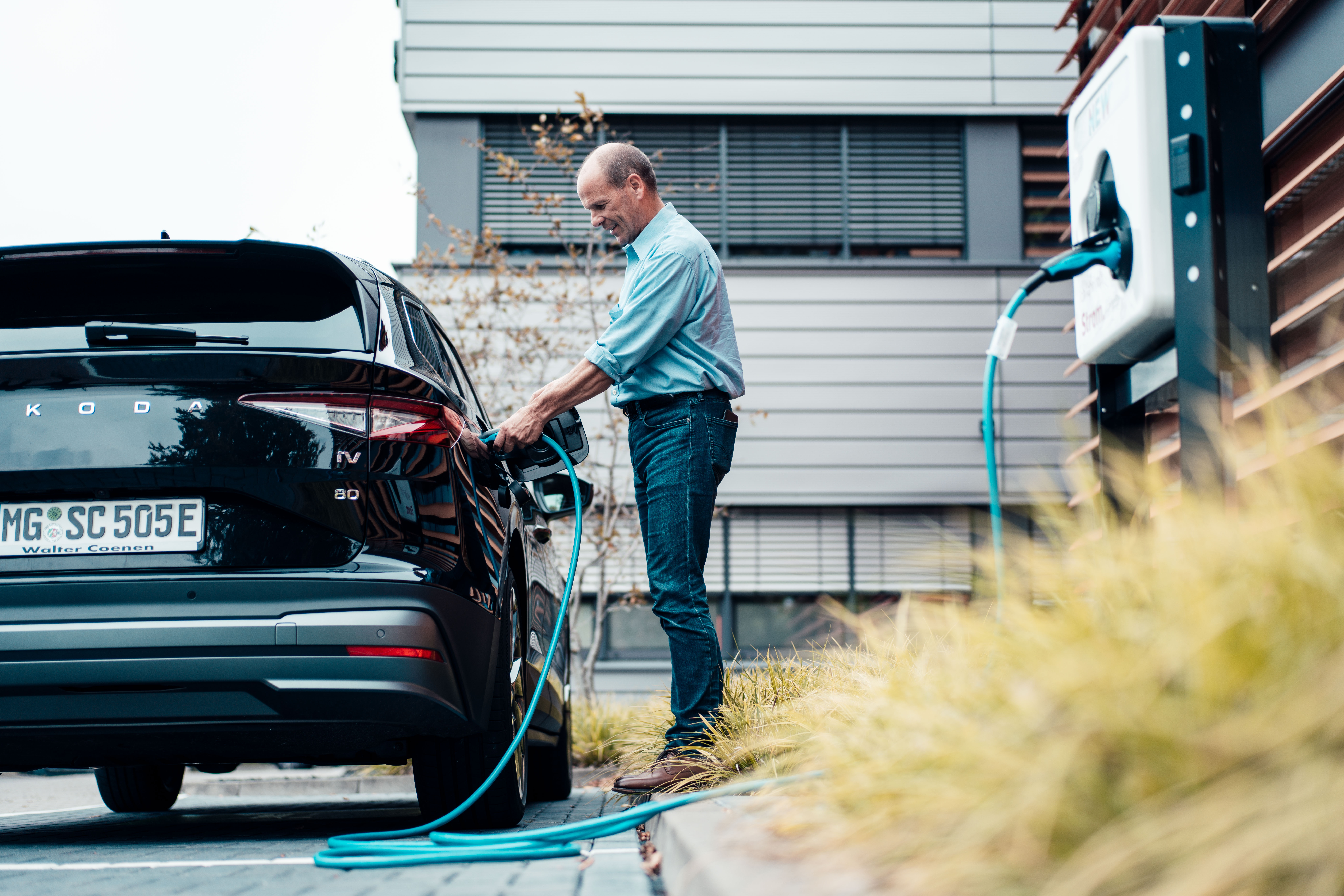 Ein Geschäftsmann lädt sein E-Auto über die NEW Ladesäule auf.
