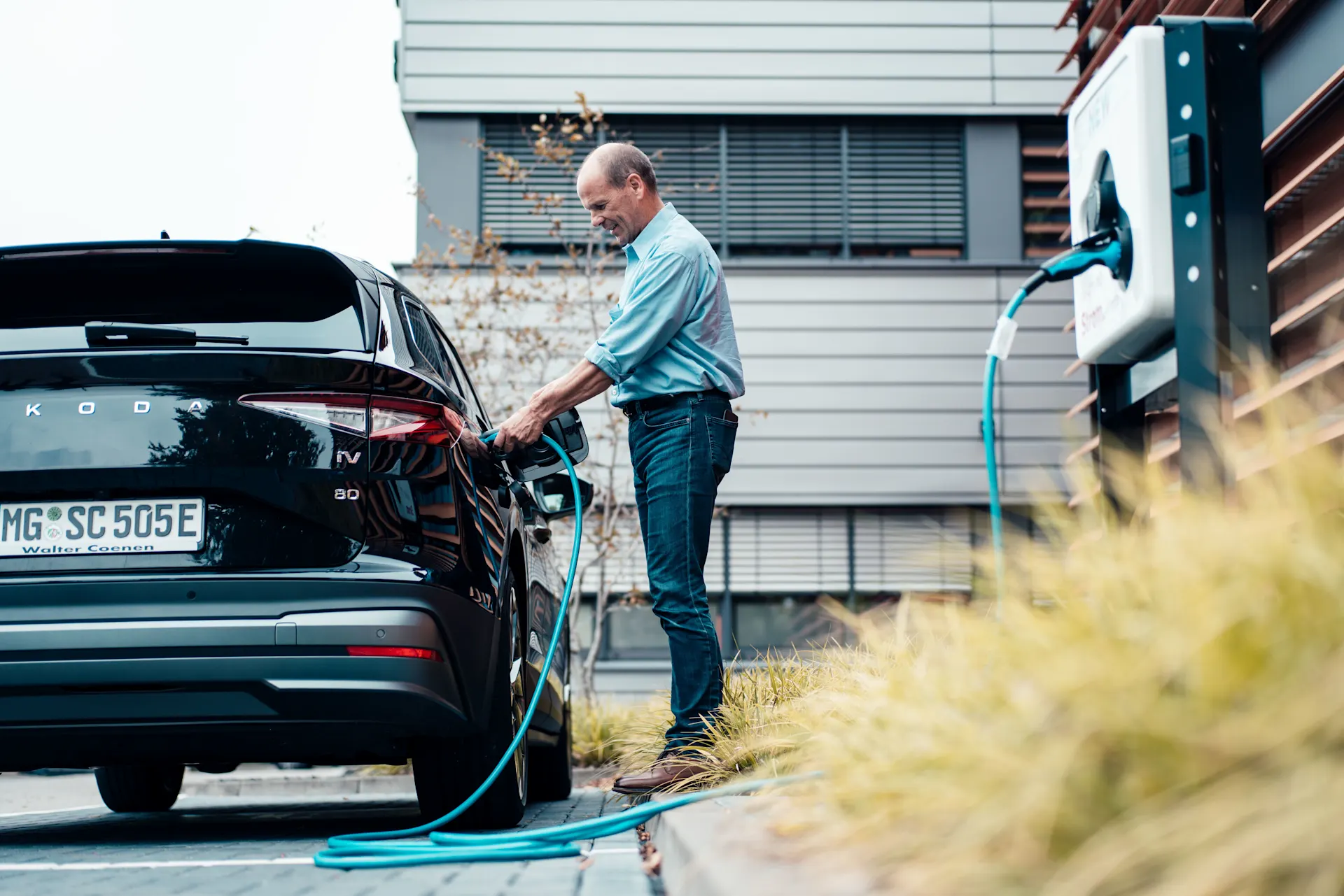 Ein Geschäftsmann lädt sein E-Auto über die NEW Ladesäule auf.