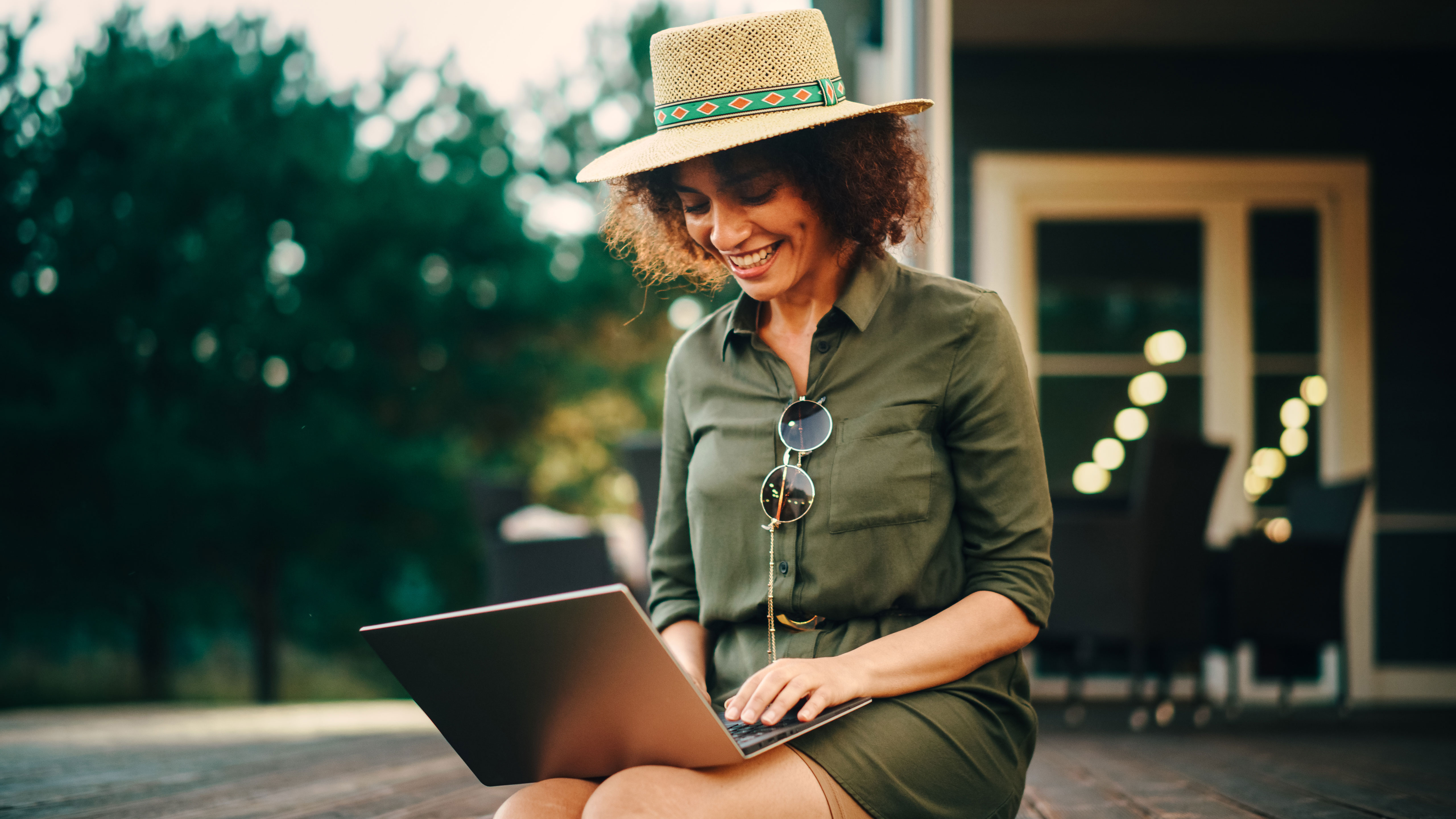 Frau sitzt mit einem Laptop auf dem Schoß im Garten und freut sich über die einfache Meldung des Umzugs bei der NEW Energie.