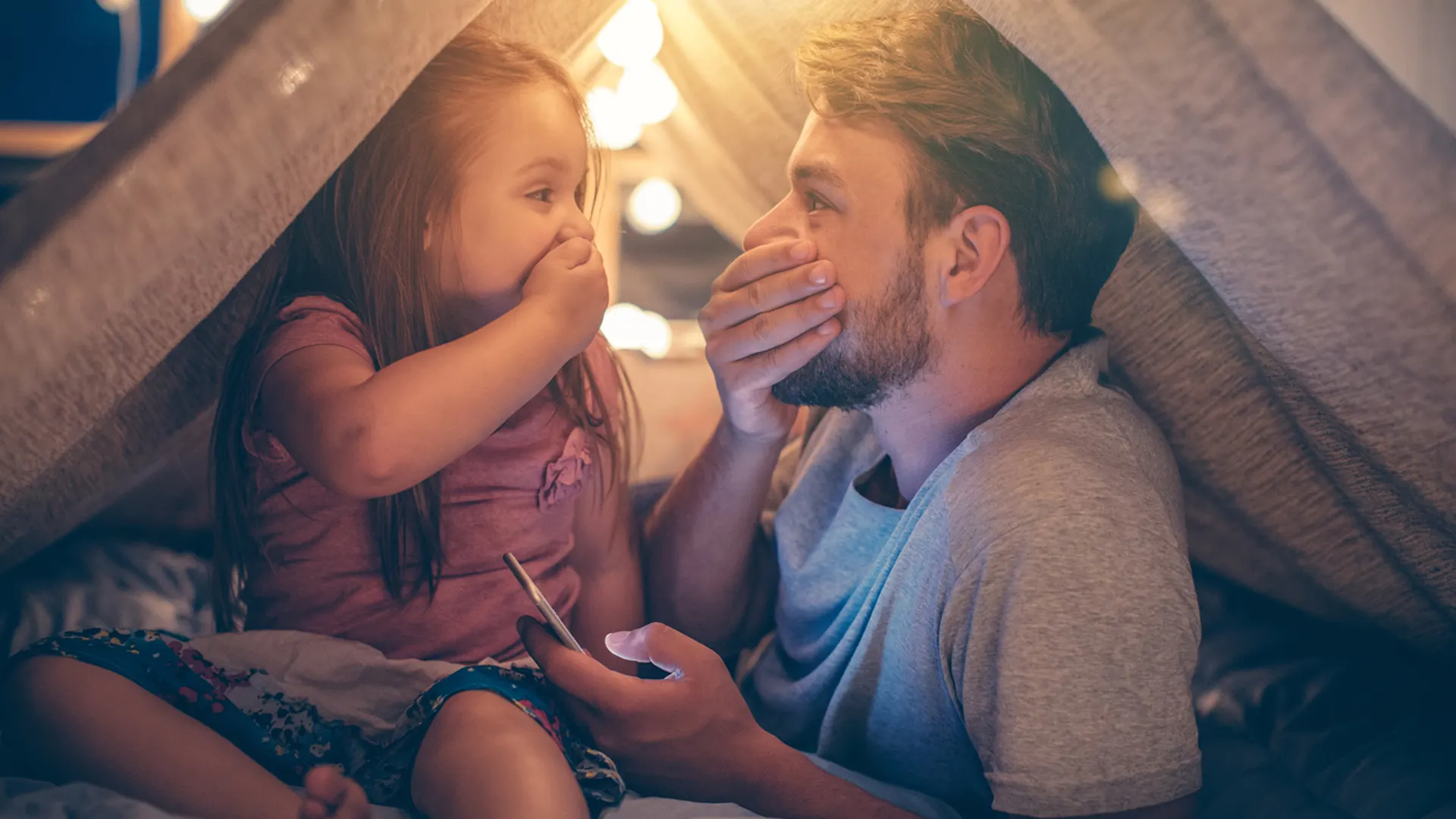 Vater und Tochter freuen sich über günstigen Strom Vater und Tochter sitzen im Wohnzimmer unter einer Deckenhöhle und freuen sich über günstigen Strom der NEW Energie.