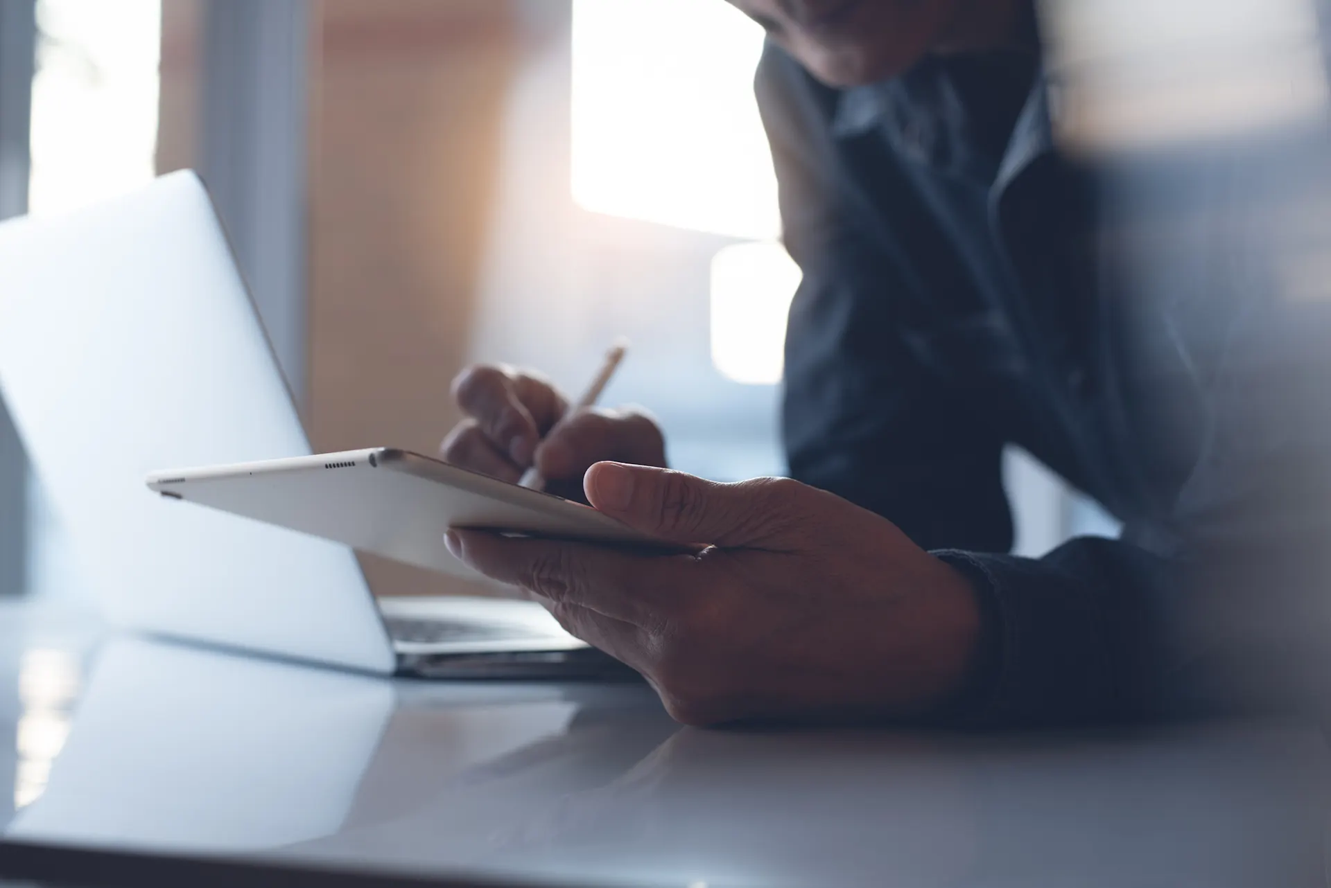 Vertriebspartner werden für NEW Energie Ein Mann lehnt über einem Tisch, mit einem Tablet in der Hand und schaut sich die Tarife der NEW Energie an.